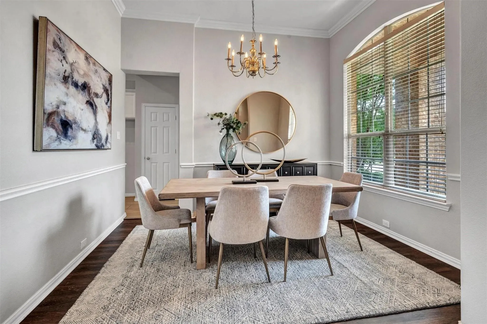Dark wood-finish flooring with crisp white baseboards and chair rail molding