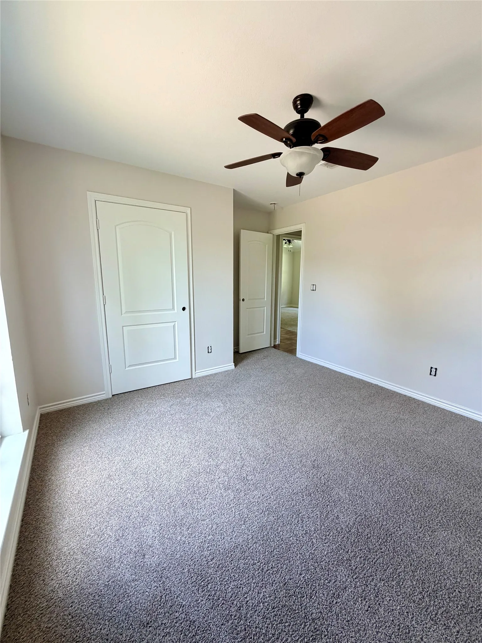Plush carpeting, ceiling fan with integrated lighting, white interior doors, and neutral wall tones