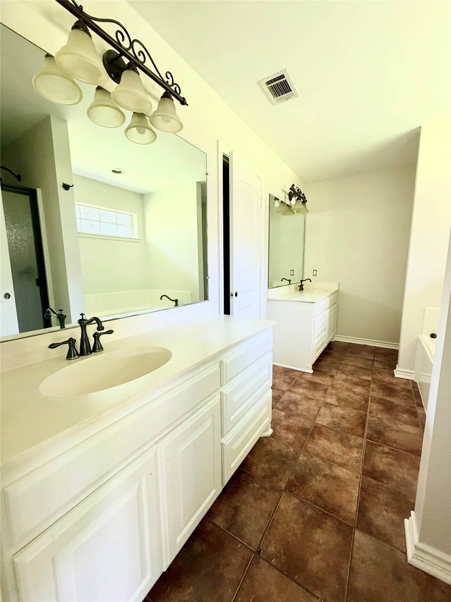 Dual vanity with integrated sinks, rich brown tile flooring, and white cabinetry