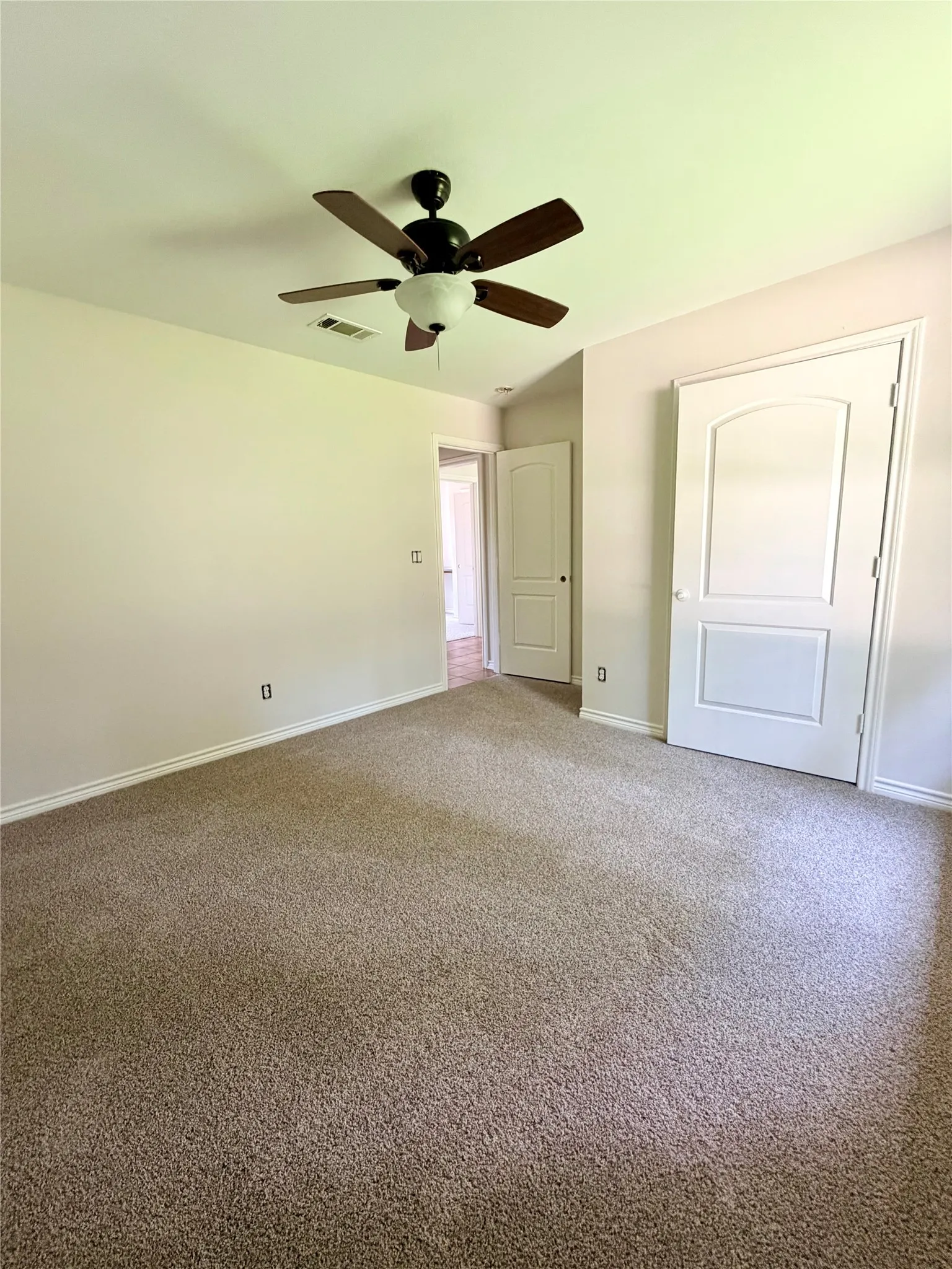 Soft carpet flooring, a ceiling fan with integrated lighting, and white paneled doors