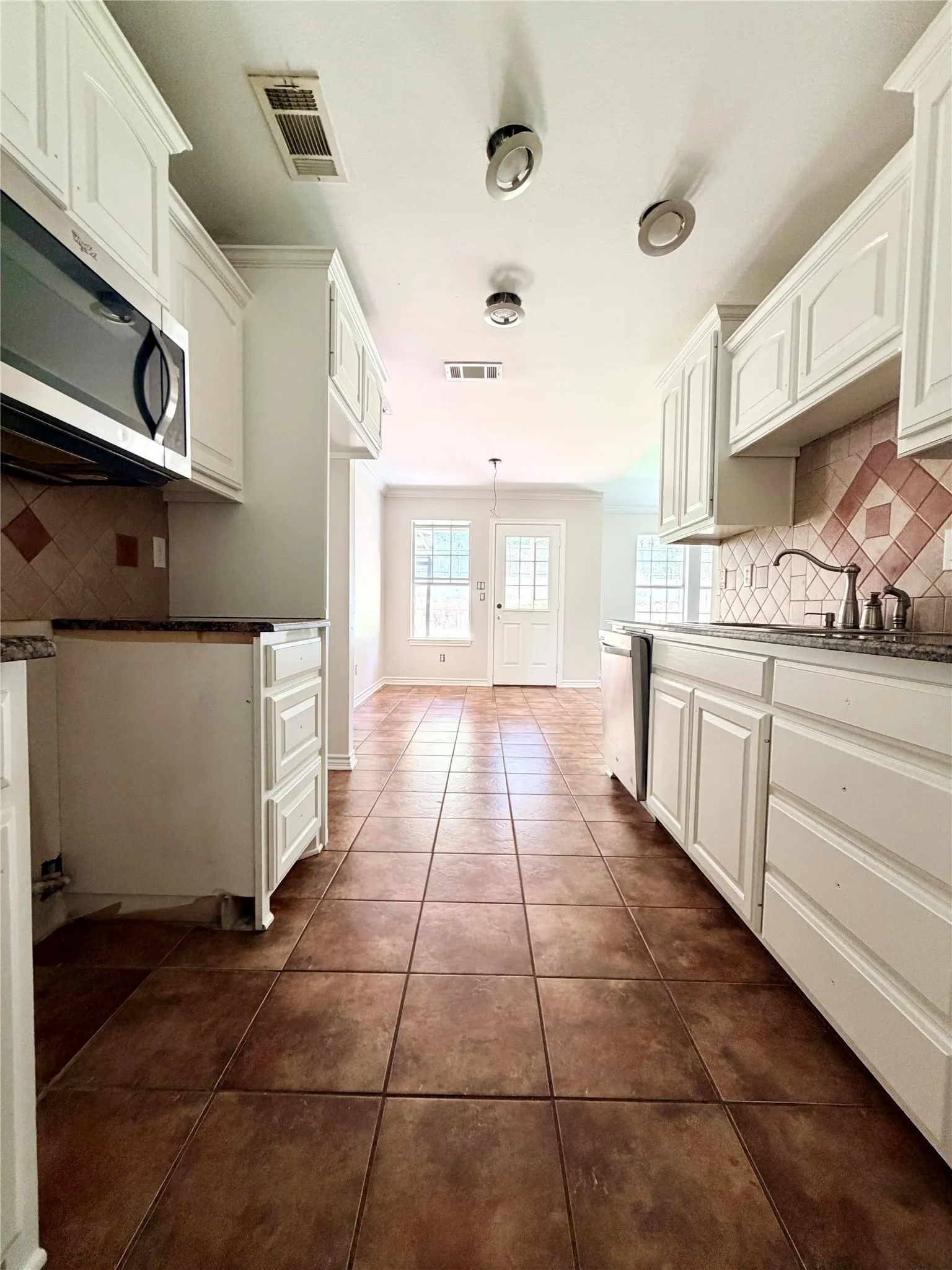 Kitchen featuring white cabinetry, tile flooring, and a tile backsplash