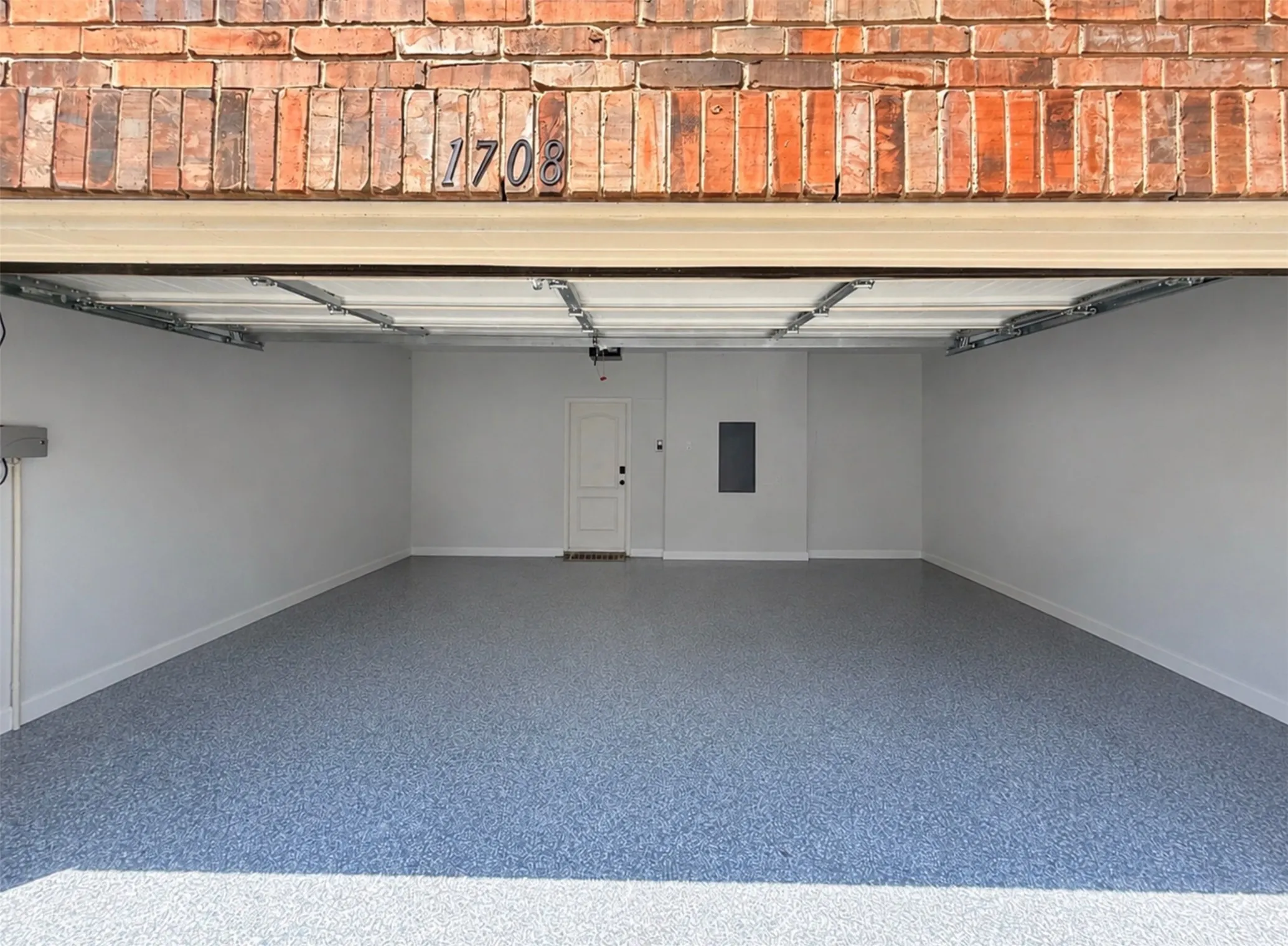 Spacious garage featuring a durable epoxy-coated floor, painted walls, and a service door