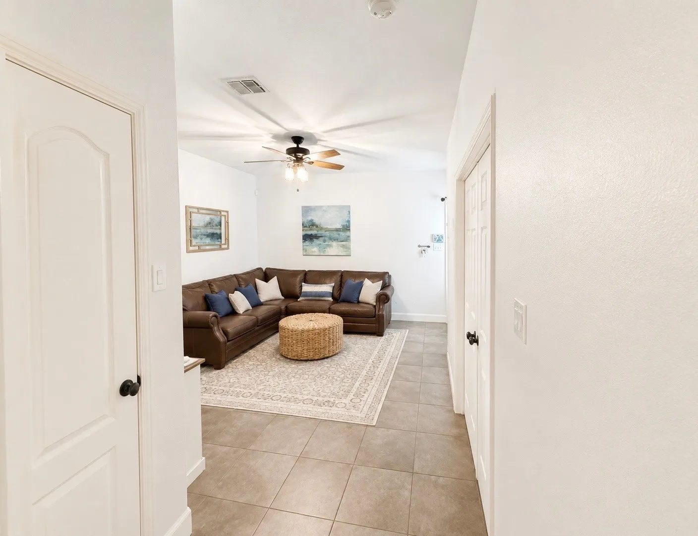 Living area featuring tile flooring, a ceiling fan with integrated lighting, and white walls