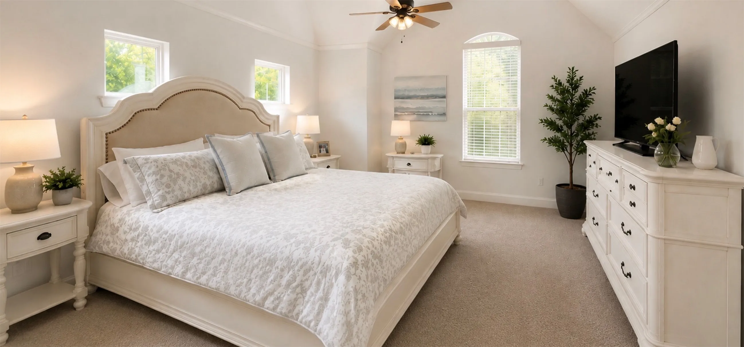 Vaulted ceiling room featuring beige carpeting, multiple windows, and a ceiling fan with light fixture