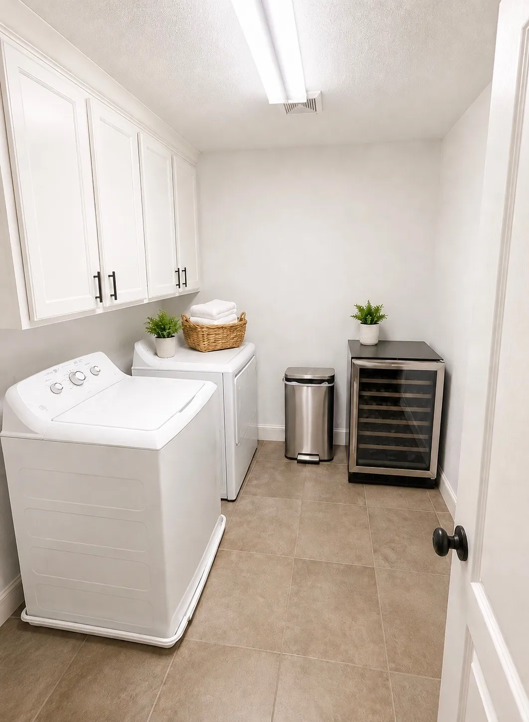 Laundry area featuring white cabinetry with dark hardware, a tiled floor, and a flush-mounted ceiling light fixture