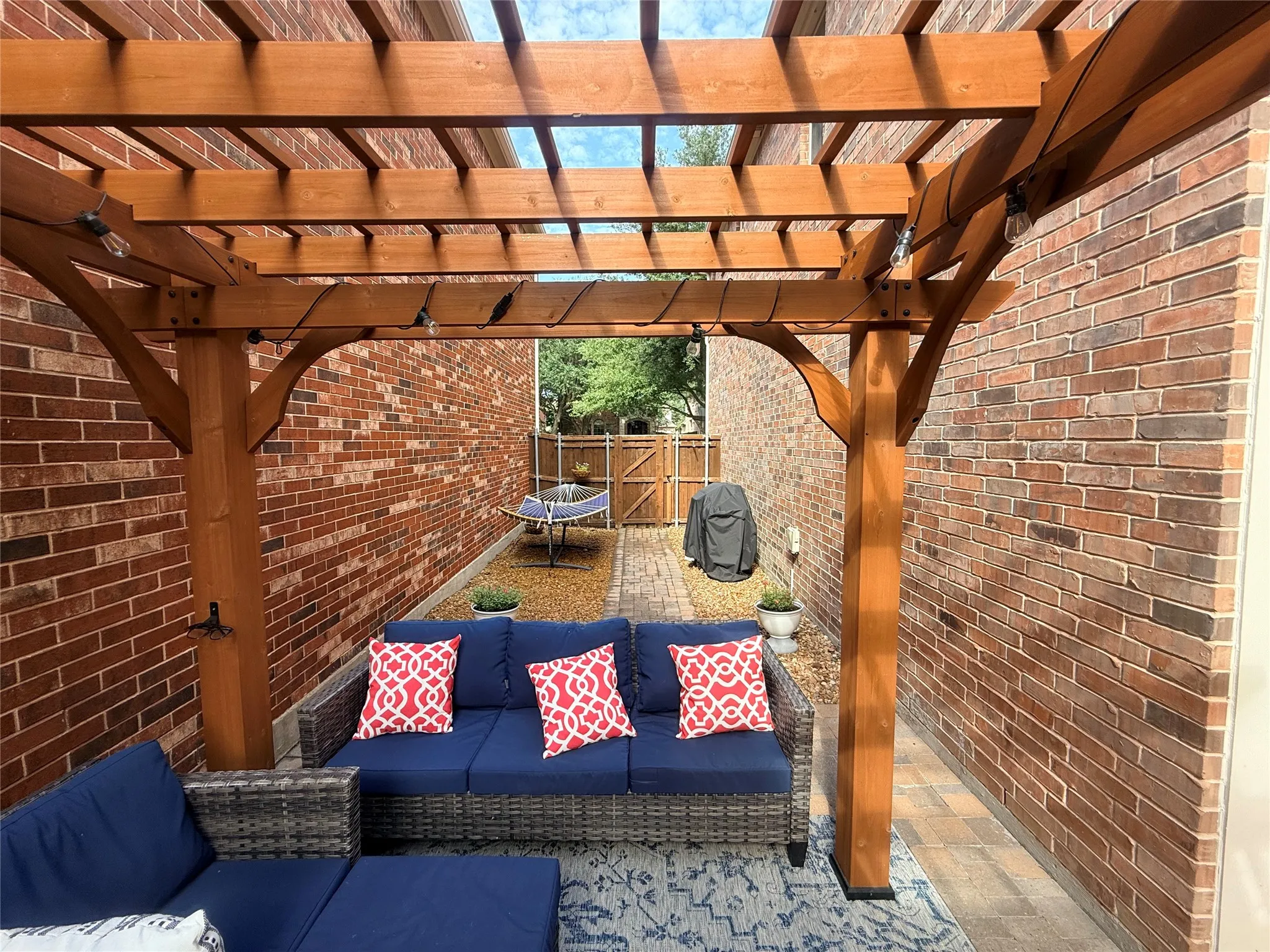 Private outdoor patio featuring a wooden pergola with integrated string lighting