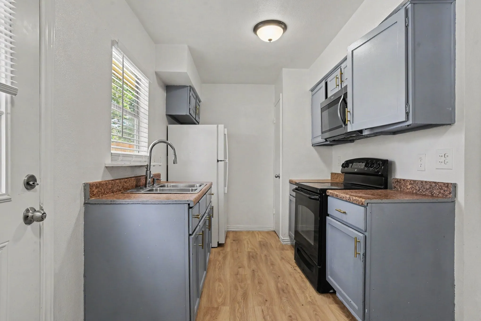 Kitchen workspace overview with upper cabinet storage, window above sink area, and built-in microwave.