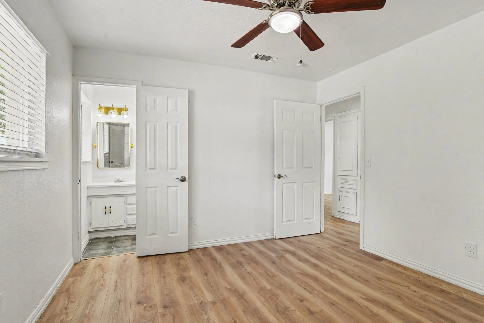 Bedroom view showing natural light, overhead fan, and en-suite doorway.