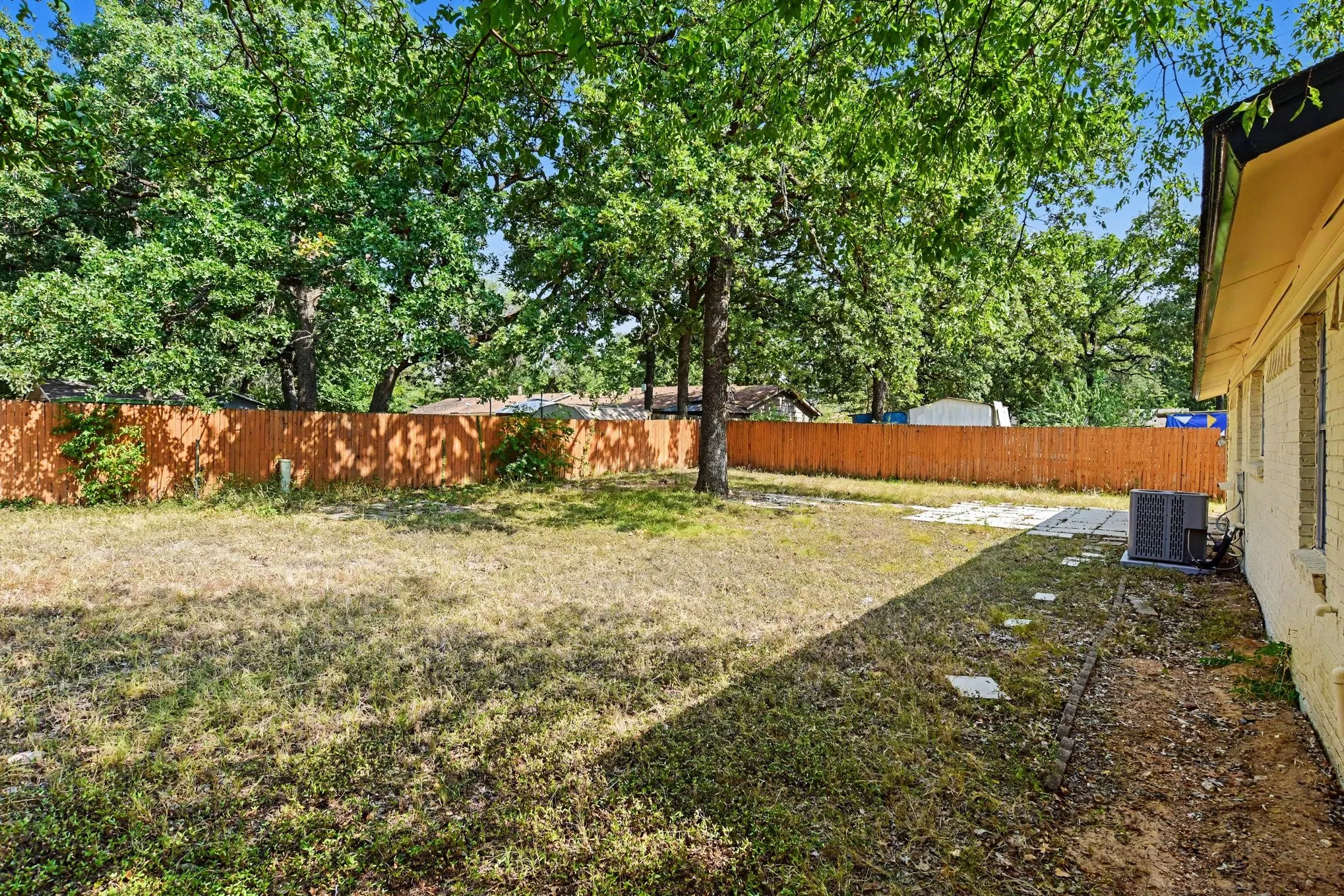 Expansive backyard area with full wood privacy fencing and shade trees.