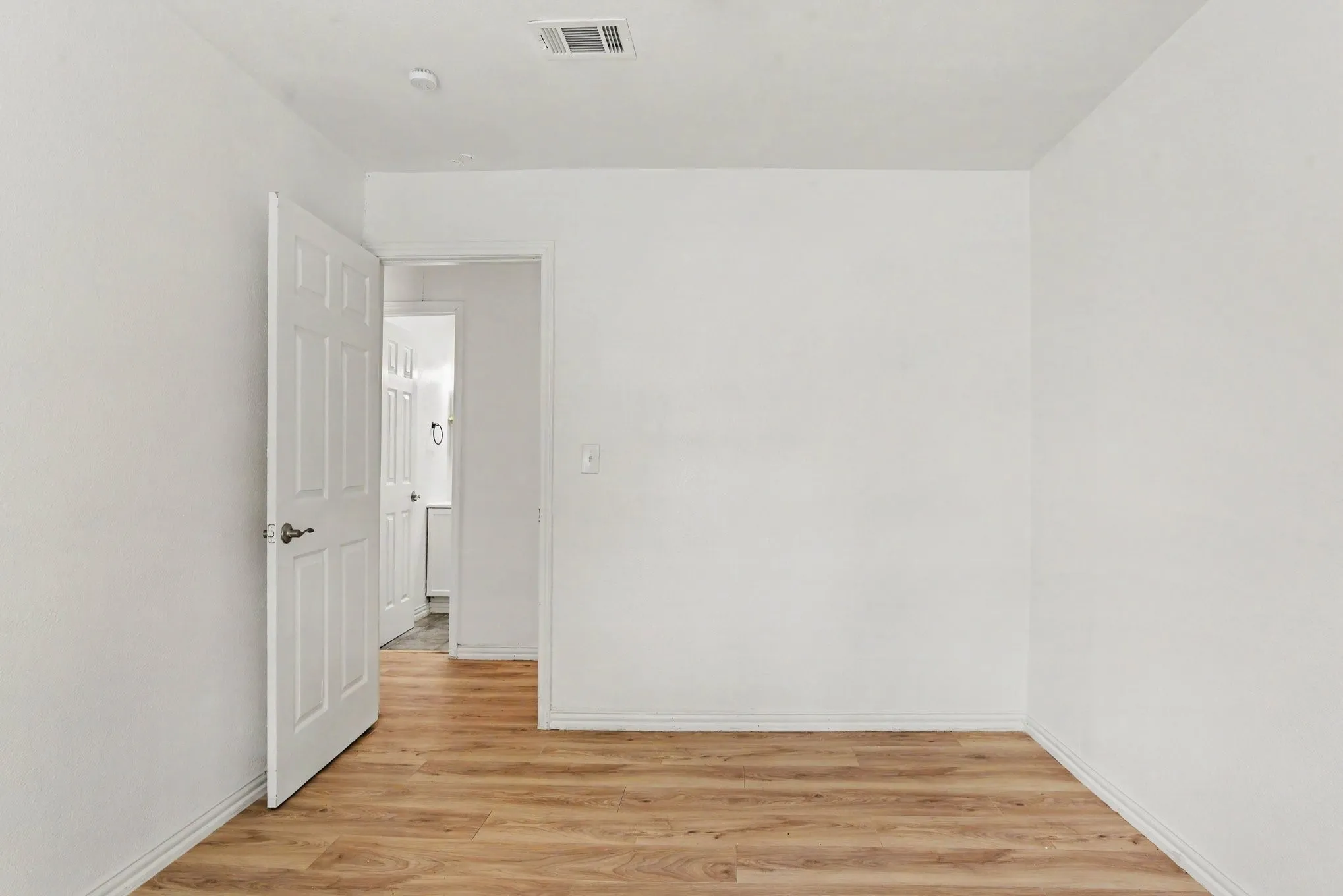 Bedroom entrance view highlighting smooth white walls, clean trim work, and neutral flooring.