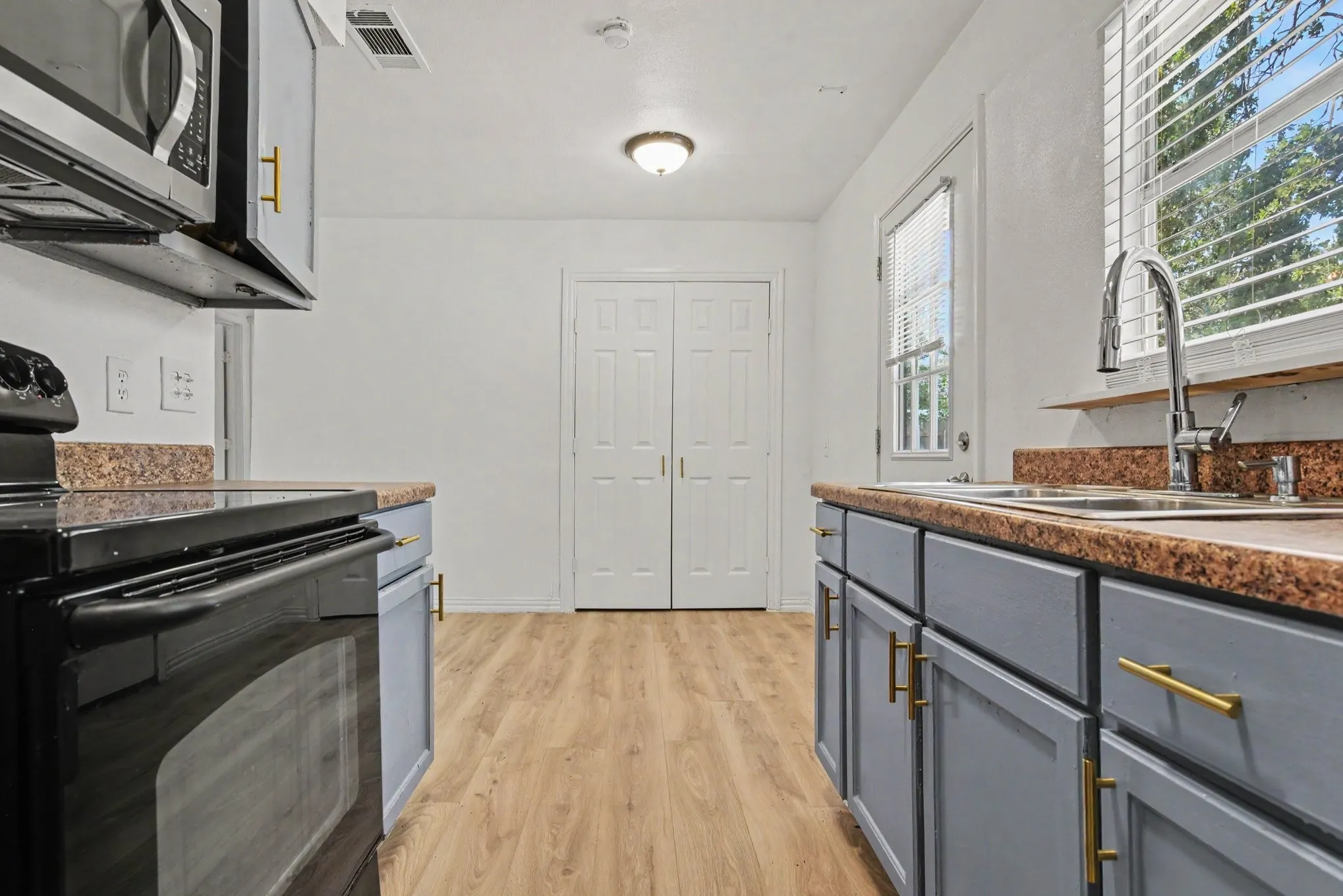 Close-up kitchen view highlighting dark countertops, double-basin sink, and modern cabinetry finishes.
