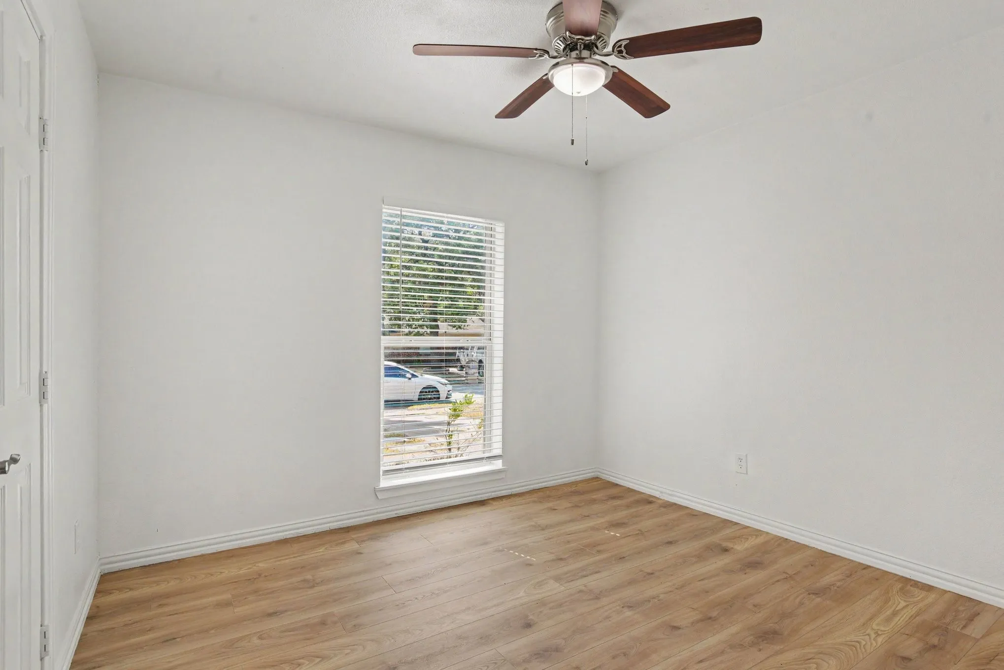 Comfortable guest bedroom with ceiling fan and view into the bright side yard.