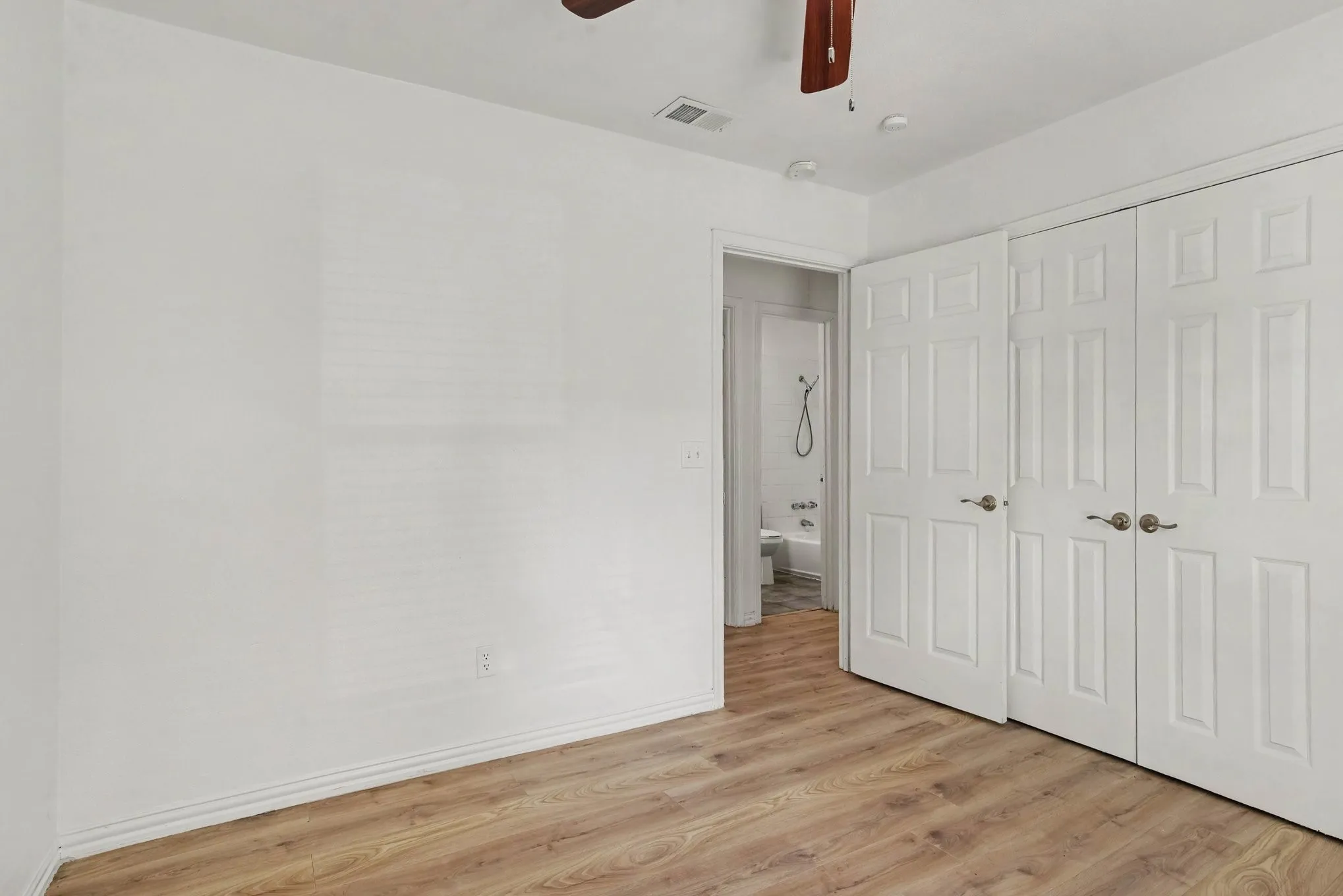 Spacious bedroom setup featuring a double closet with white bi-fold doors.