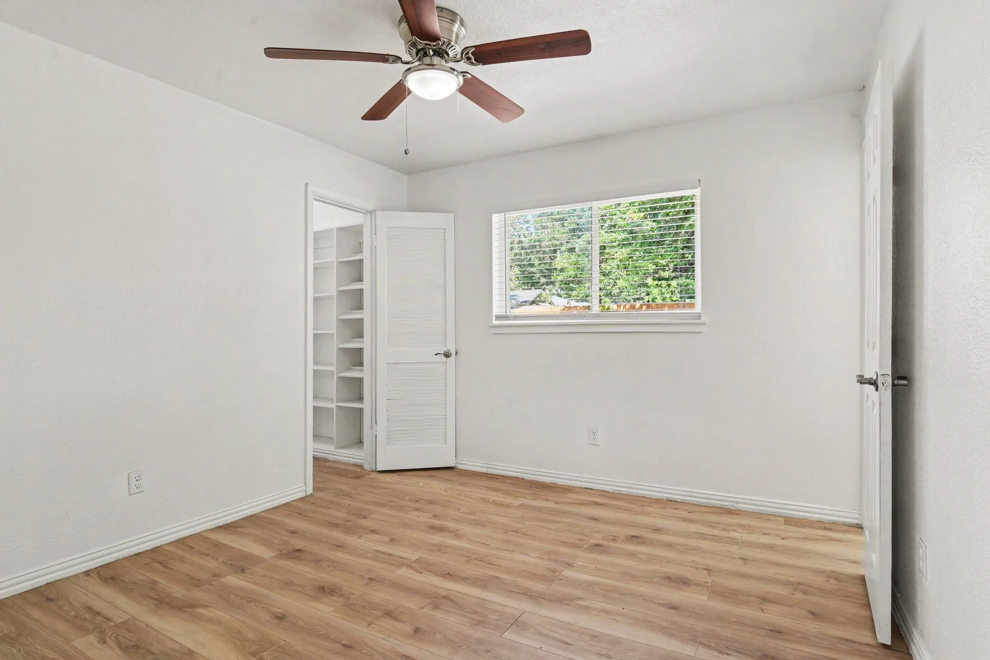 Additional bedroom view displaying generous layout, ceiling fan, and light-filled window.