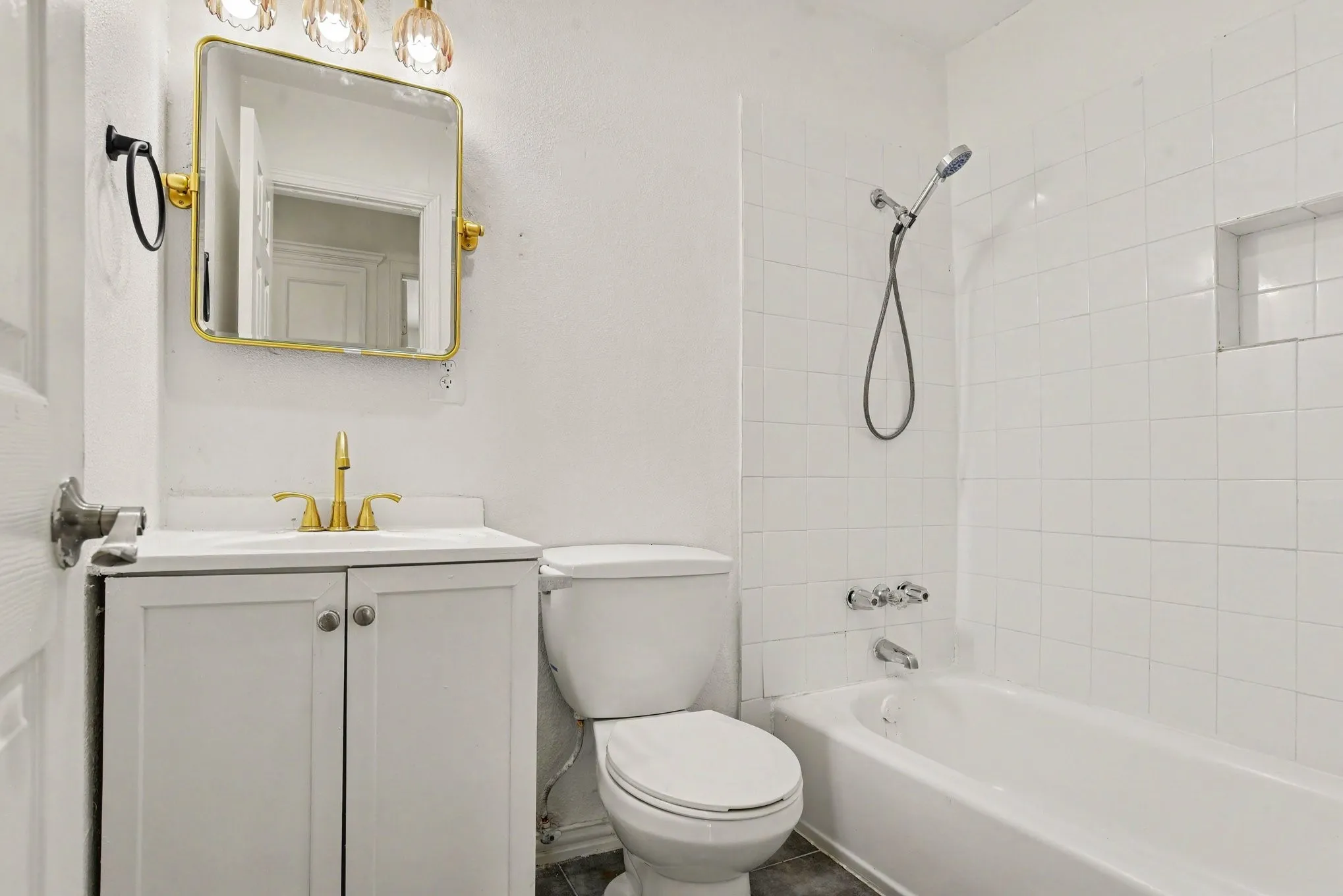 Full bathroom equipped with a updated vanity, gold fixtures, toilet, and tiled tub/shower combo.
