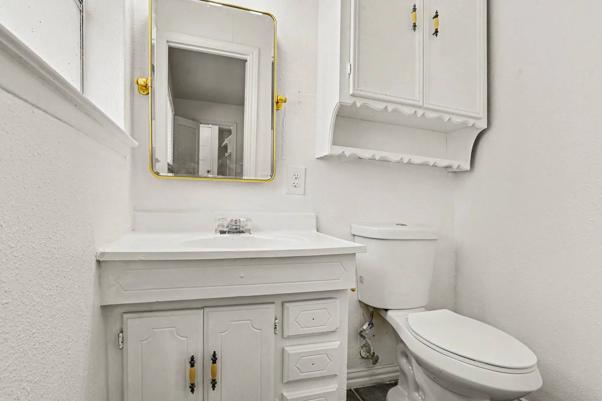 Primary bathroom featuring a white vanity with gold hardware, framed mirror, and upper medicine cabinet.