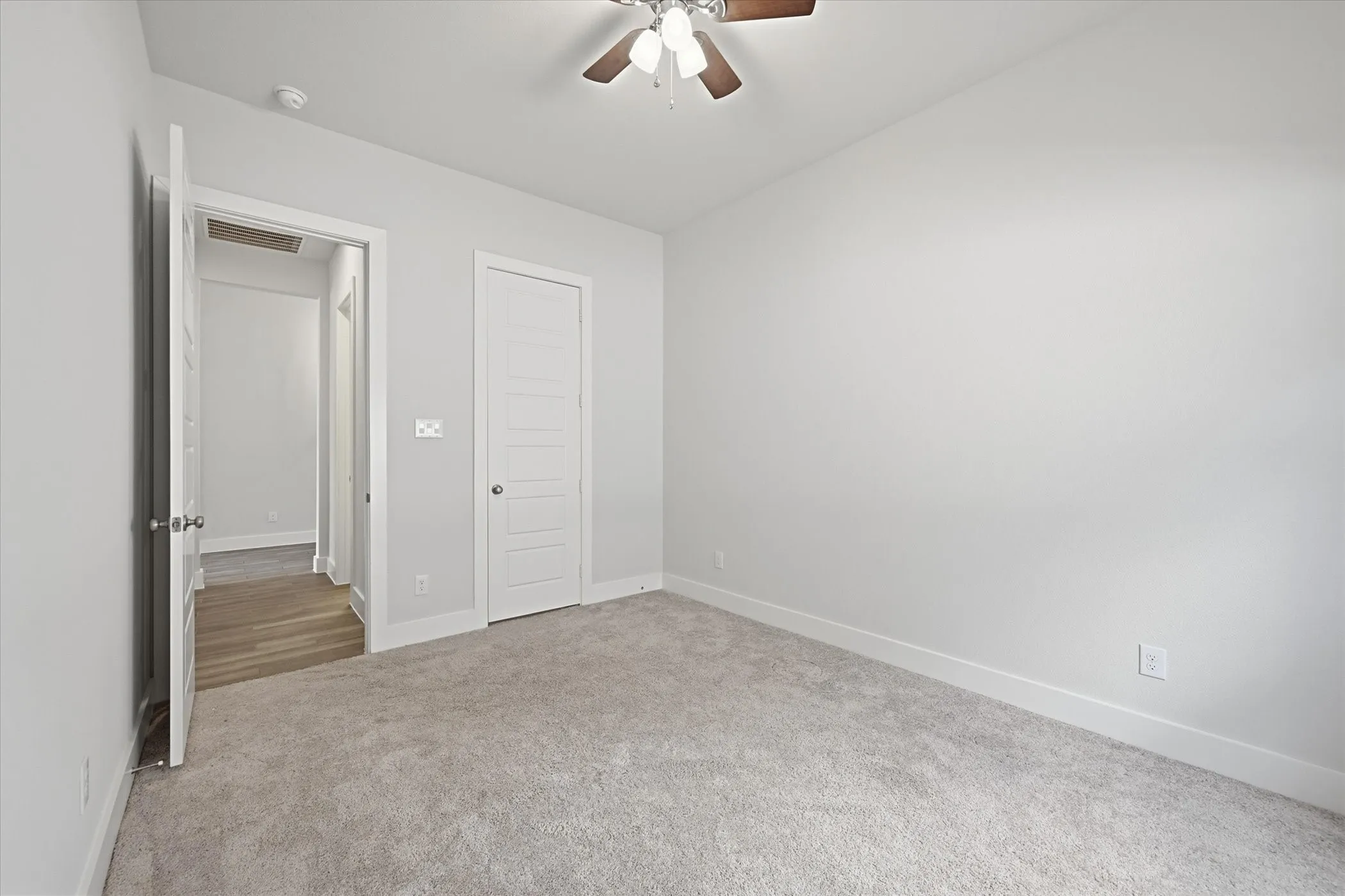 Neutral wall paint, ceiling fan with light fixture, carpet flooring, paneled interior door, and white trim work
