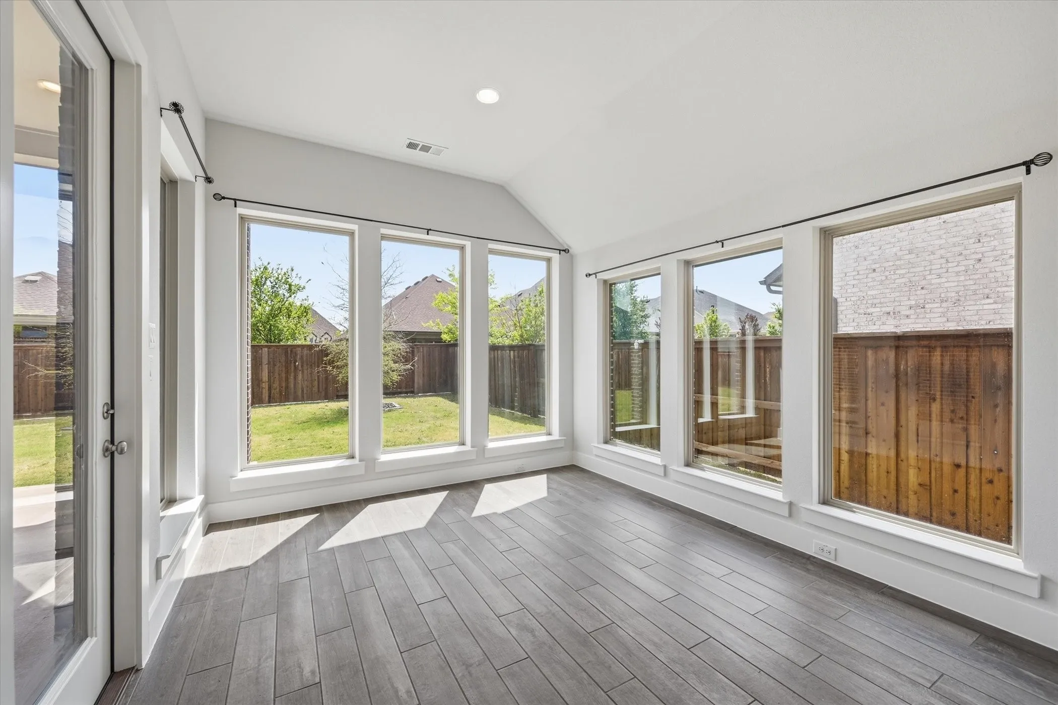 Room with wood-finish flooring, vaulted ceiling, and recessed lighting