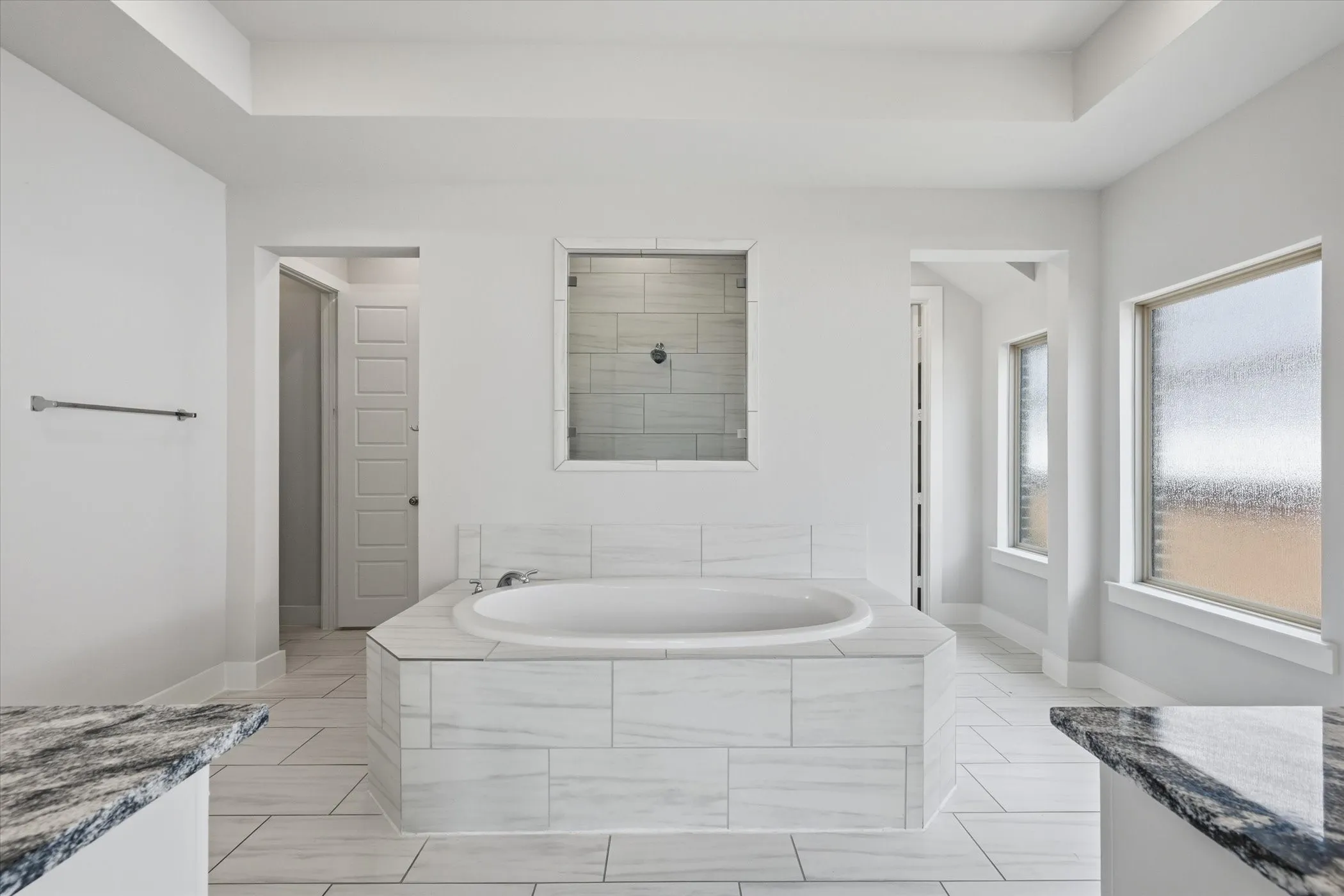 Soaking tub with white tile surround, adjacent glass-enclosed shower, white tile flooring, and two frosted windows