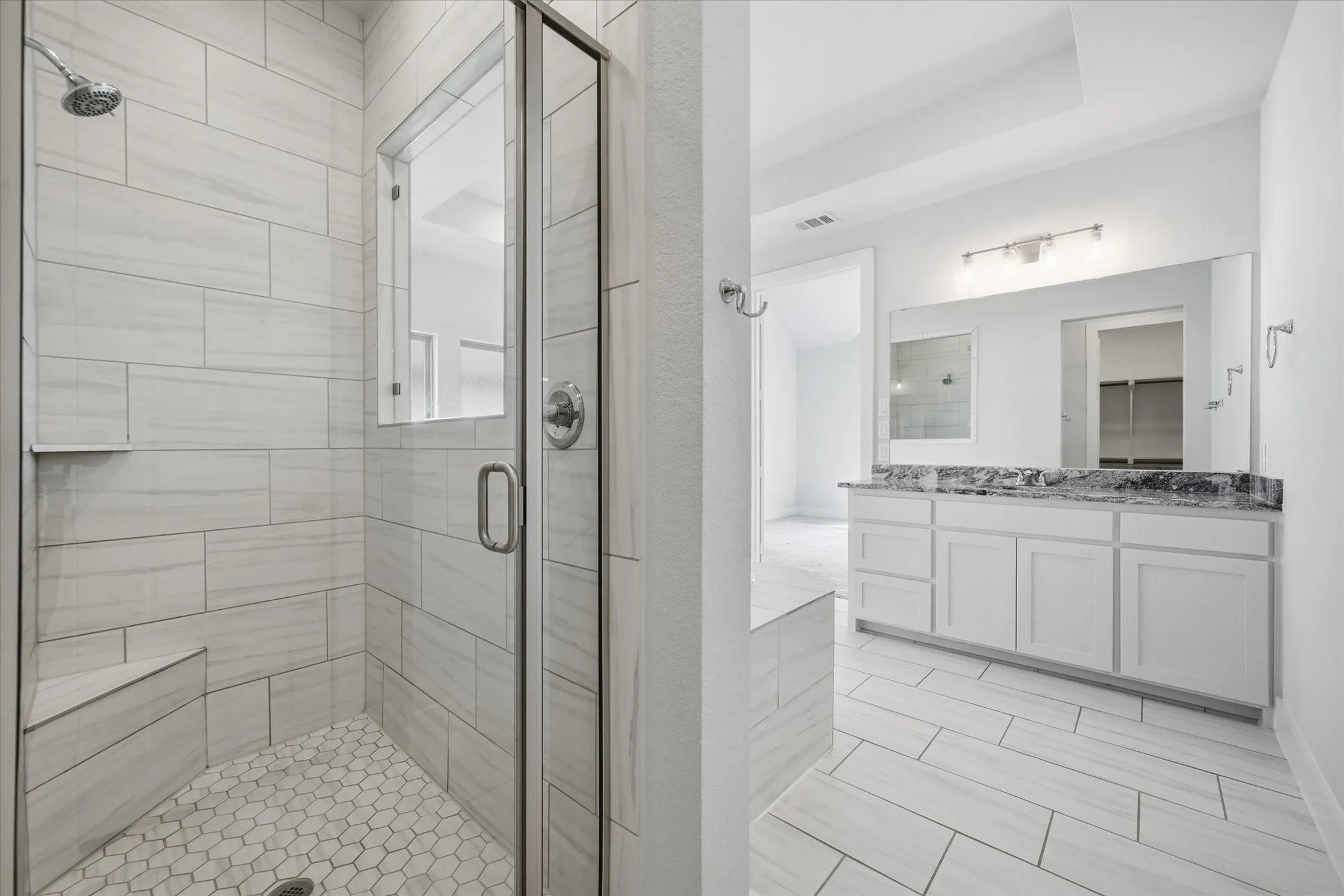 Walk-in shower with a glass enclosure, hexagon tile flooring, and a built-in bench
