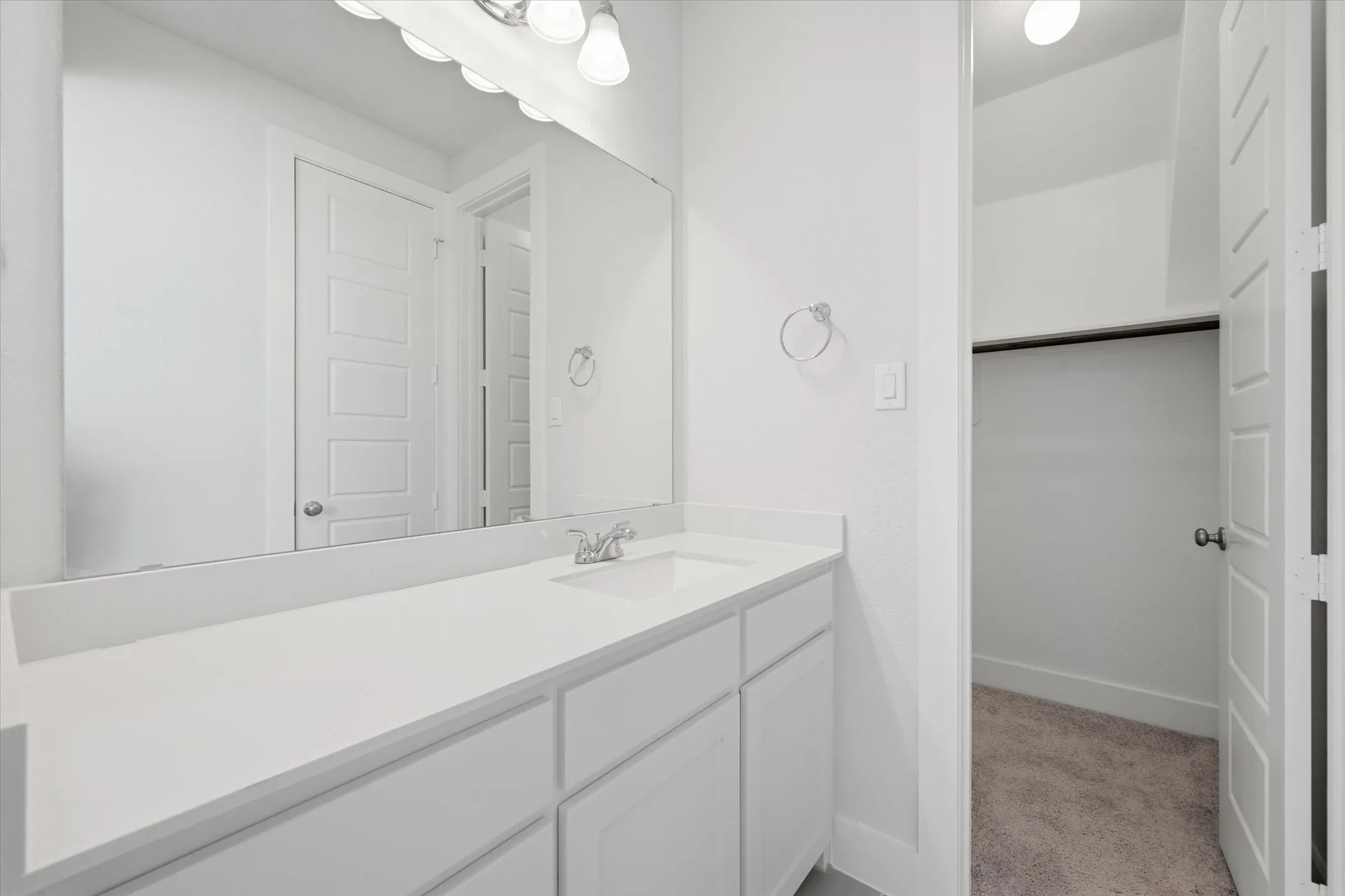 Vanity with an integrated sink, polished chrome faucet, and expansive mirror