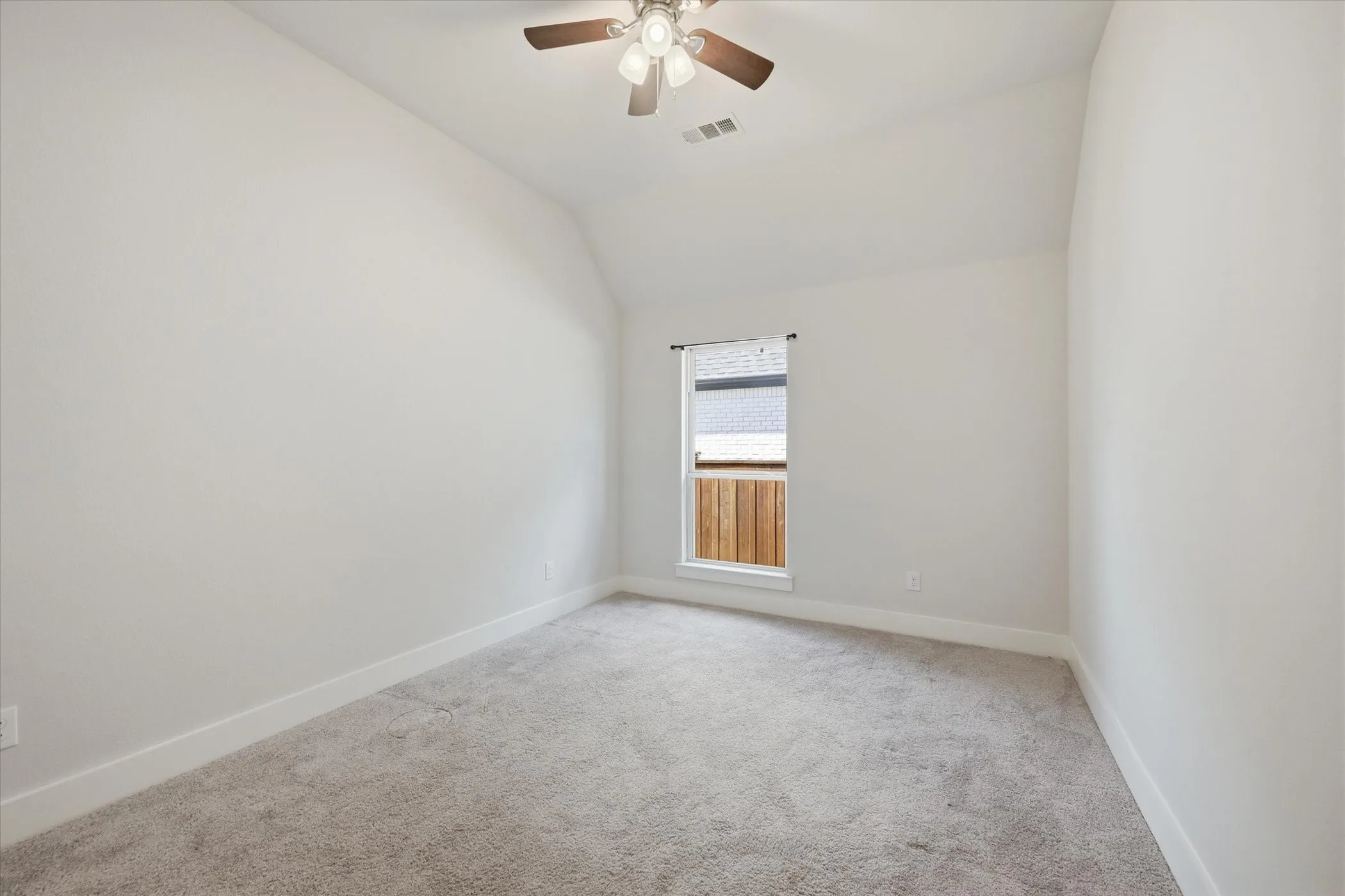 Vaulted ceiling with a ceiling fan, neutral carpeting, and a window with white trim