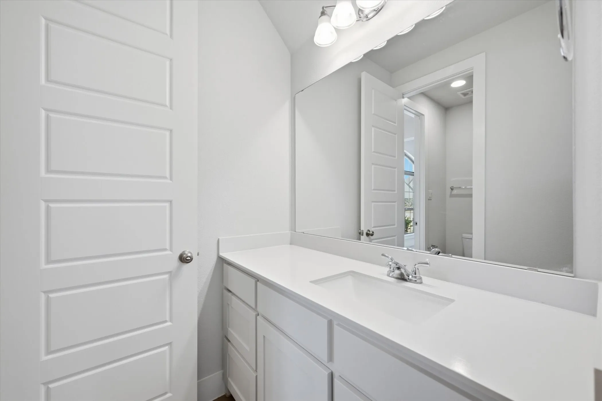 White vanity with an integrated rectangular sink, chrome faucet, and expansive countertop