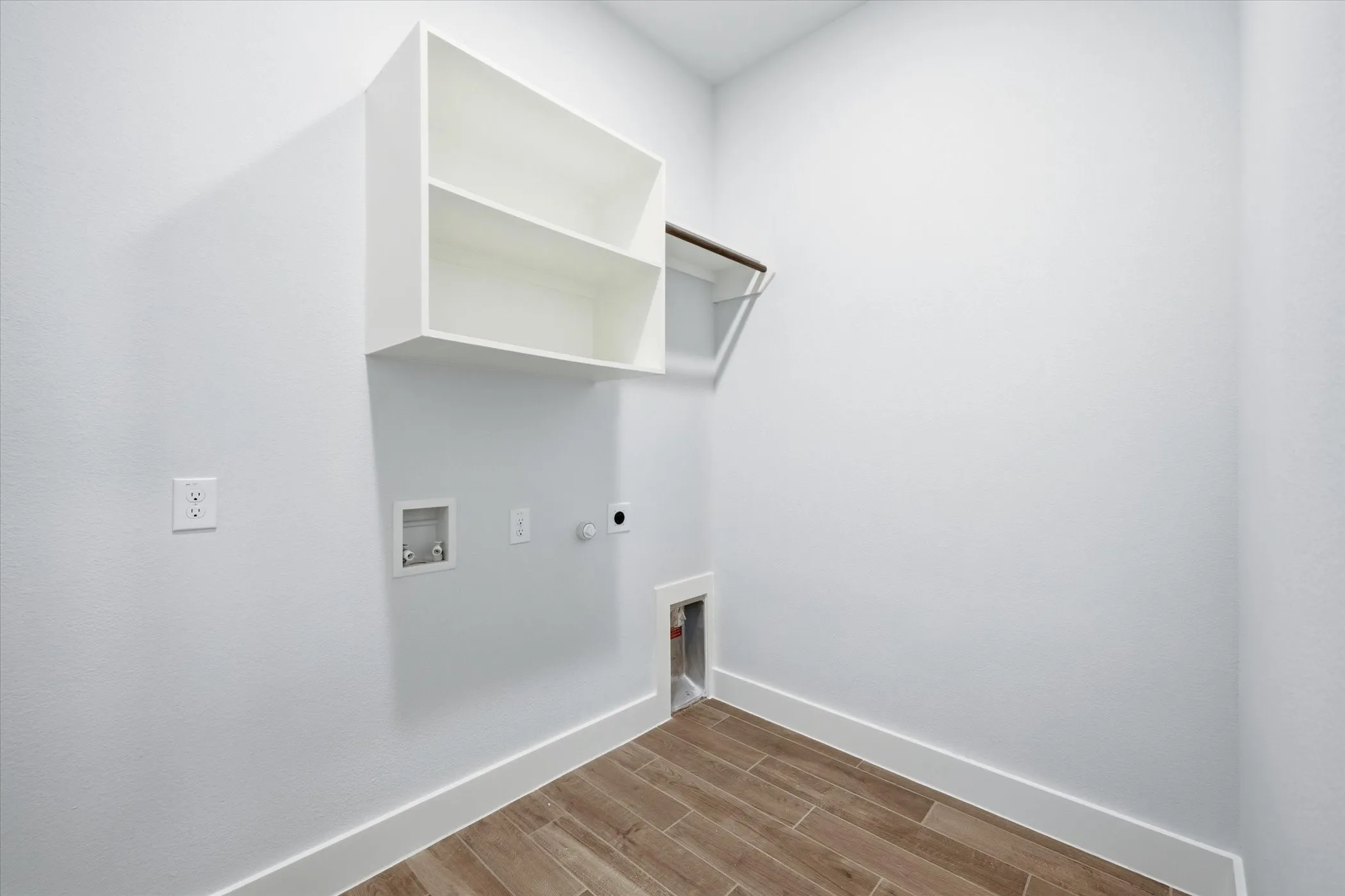 Laundry room featuring wood-finish tile flooring, white built-in shelving, and a hanging rod