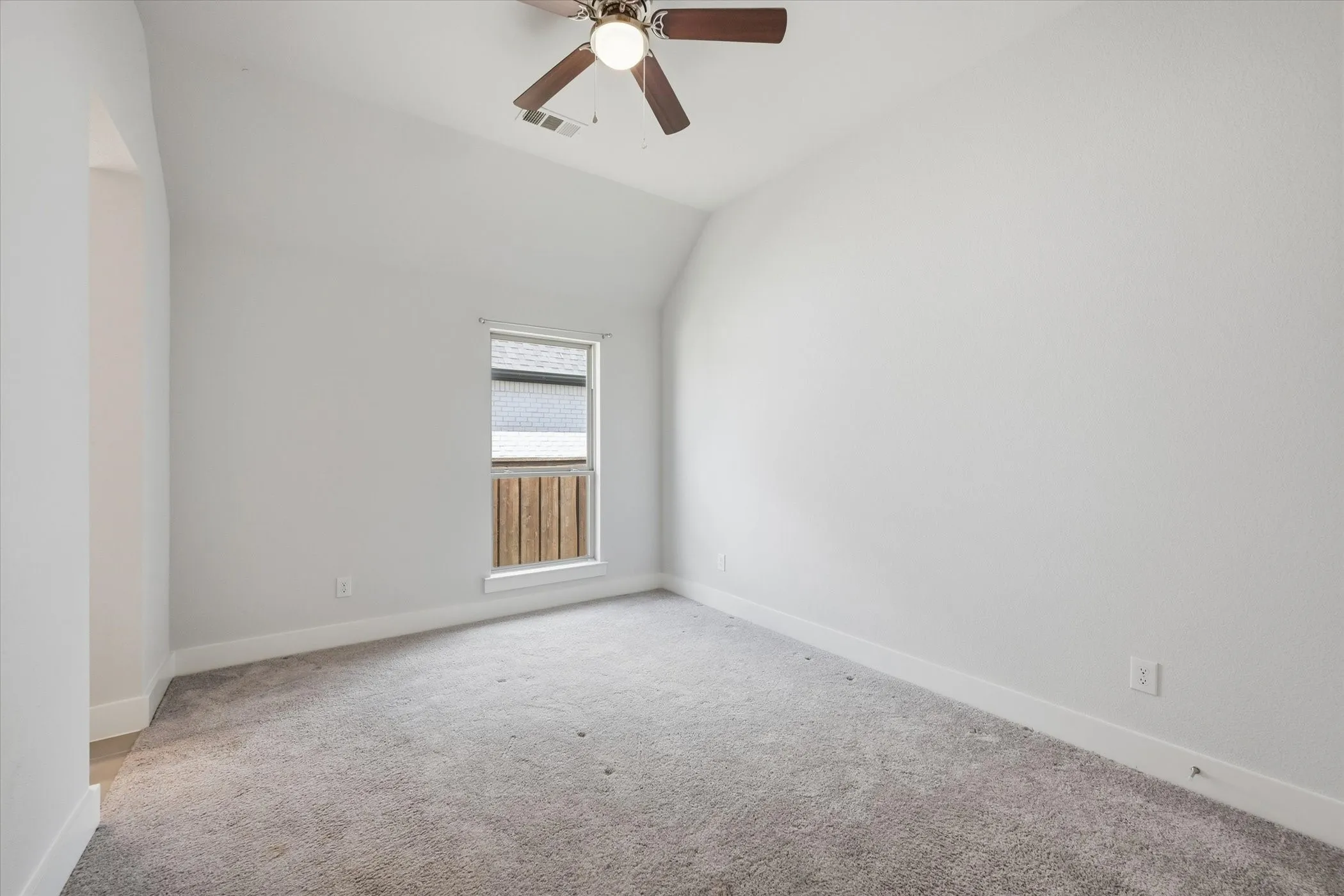 Vaulted ceiling with an attached ceiling fan, single window, and carpeted flooring