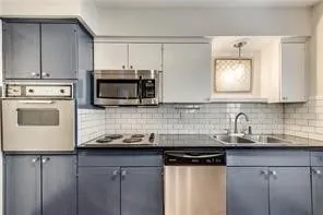 Updated kitchen featuring stainless steel appliances, including a dishwasher and microwave, paired with dual-tone cabinetry in navy and cream finishes
