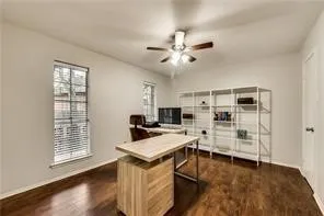 Wood-finish flooring, multiple windows, ceiling fan, and white walls