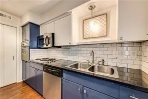 Kitchen featuring stainless steel appliances, dual basin sink, white subway tile backsplash, and dark countertops