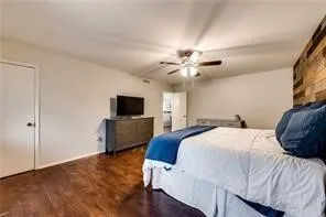 Wood-finish flooring, ceiling fan, white paneled doors, and a wood-paneled accent wall