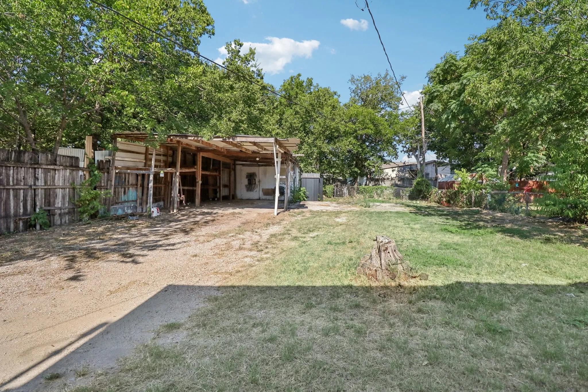 Expansive lot featuring a storage structure, gravel parking area, and mature trees