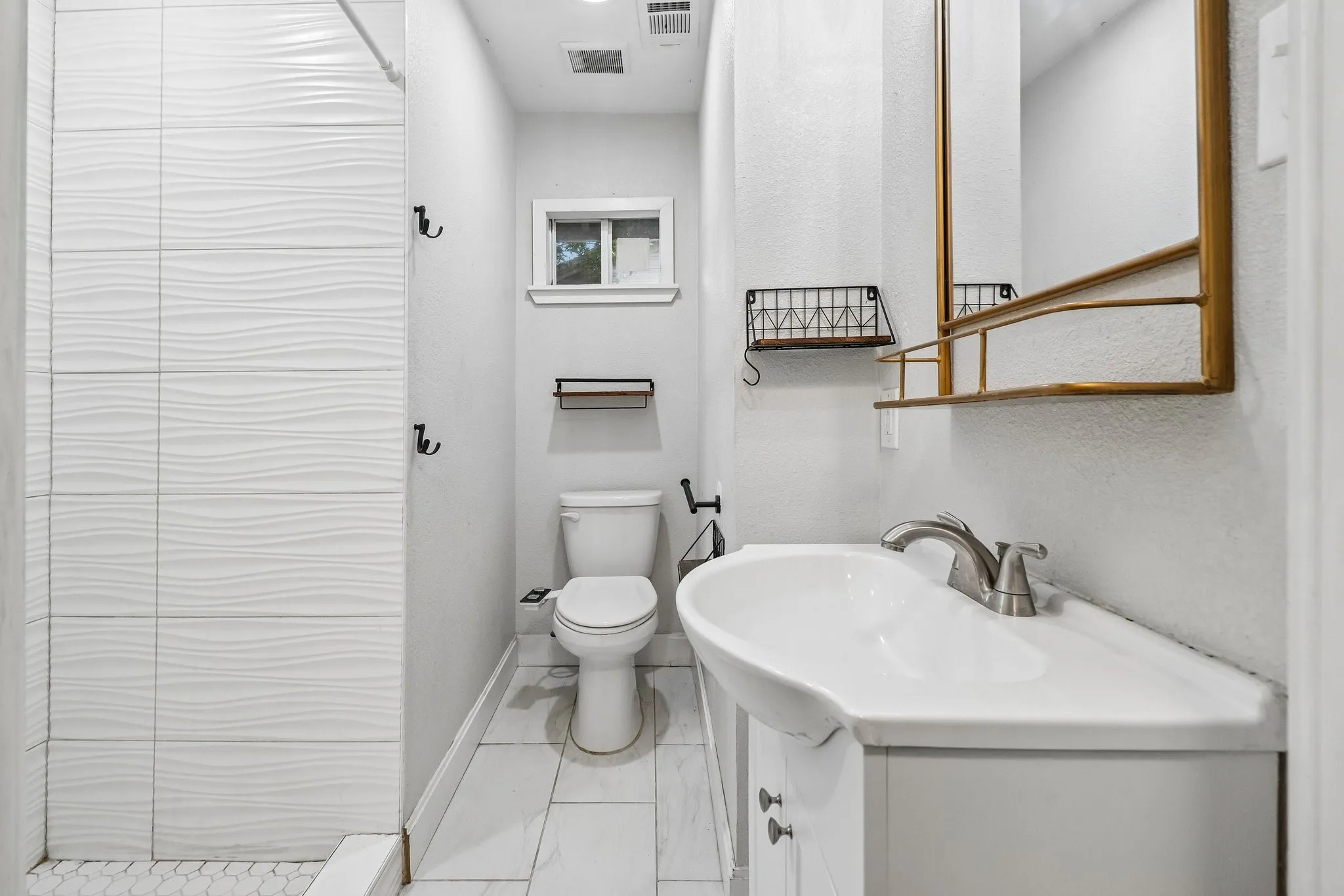 Modern bathroom featuring white subway tile shower with wave texture, large vanity mirror, white tile flooring, and built-in vanity with single basin sink