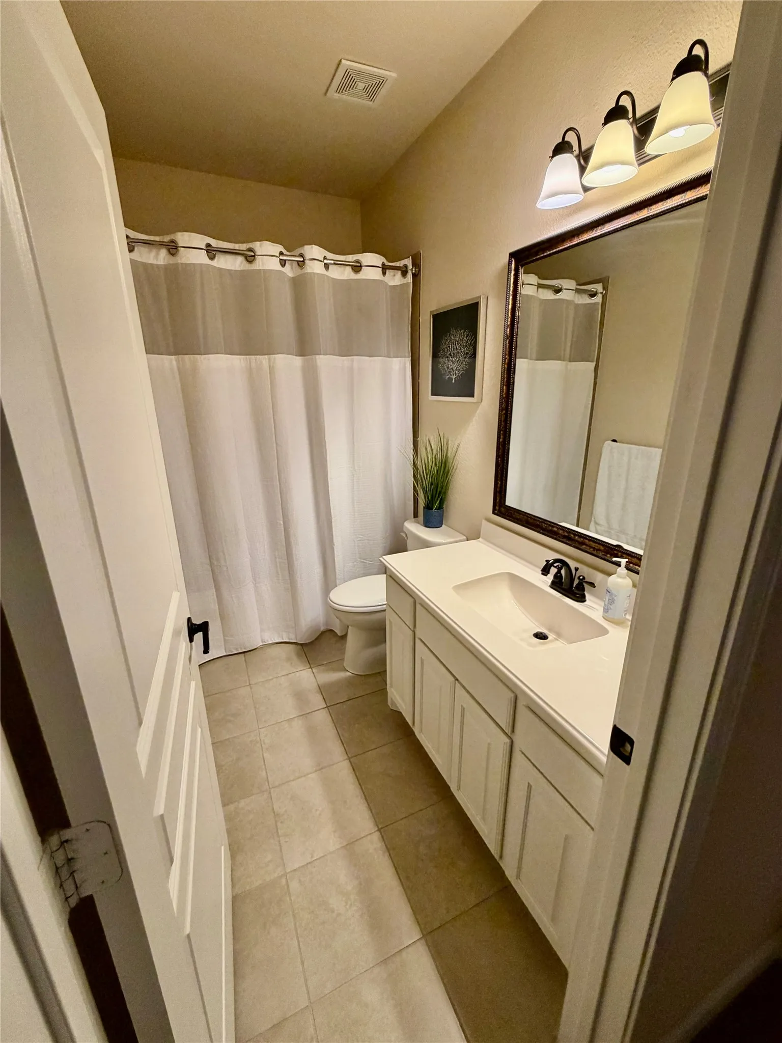 Bathroom featuring a single vanity with storage, a rectangular sink, and a dark-framed mirror