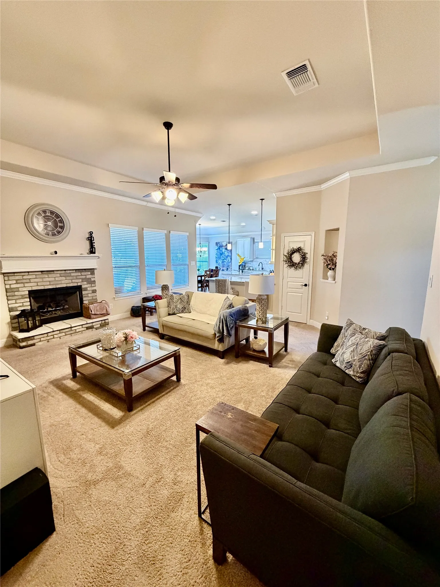 Living area featuring a brick fireplace with white mantel, multiple windows, and a ceiling fan