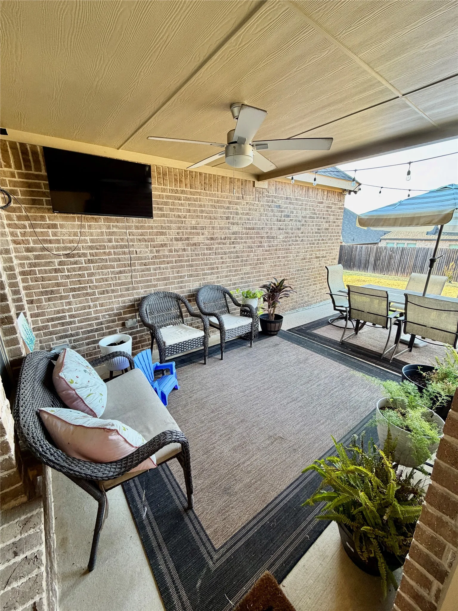 Covered patio with a mounted ceiling fan and brick wall