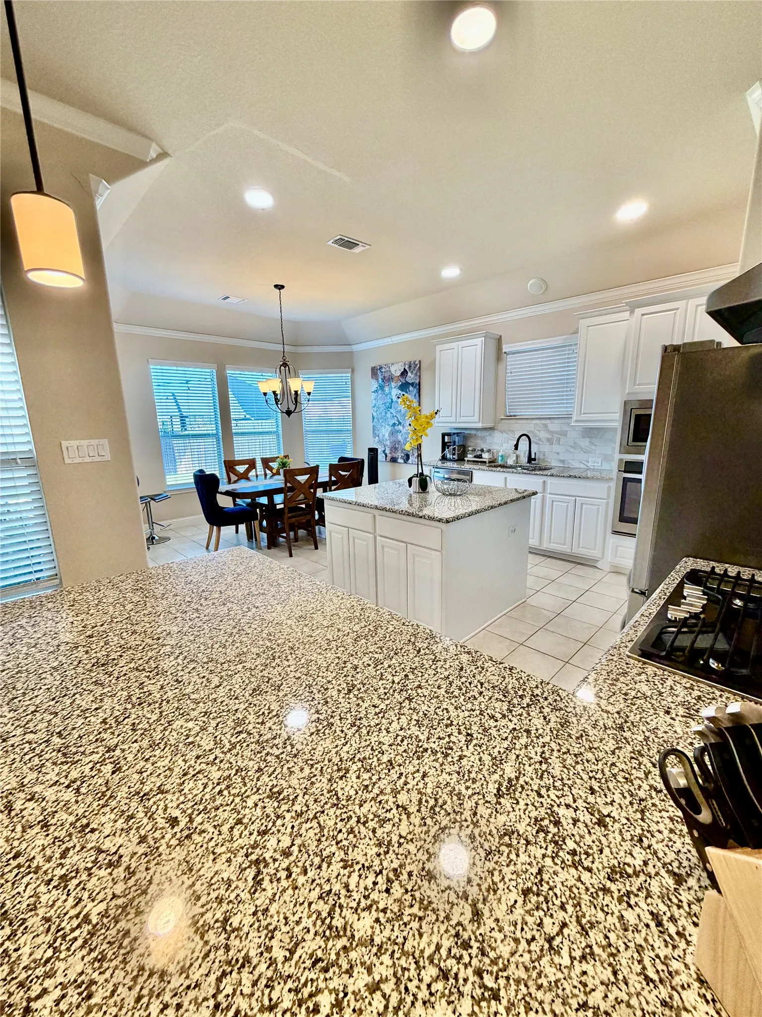Spacious kitchen featuring granite countertops, white cabinetry, a central island, and recessed lighting