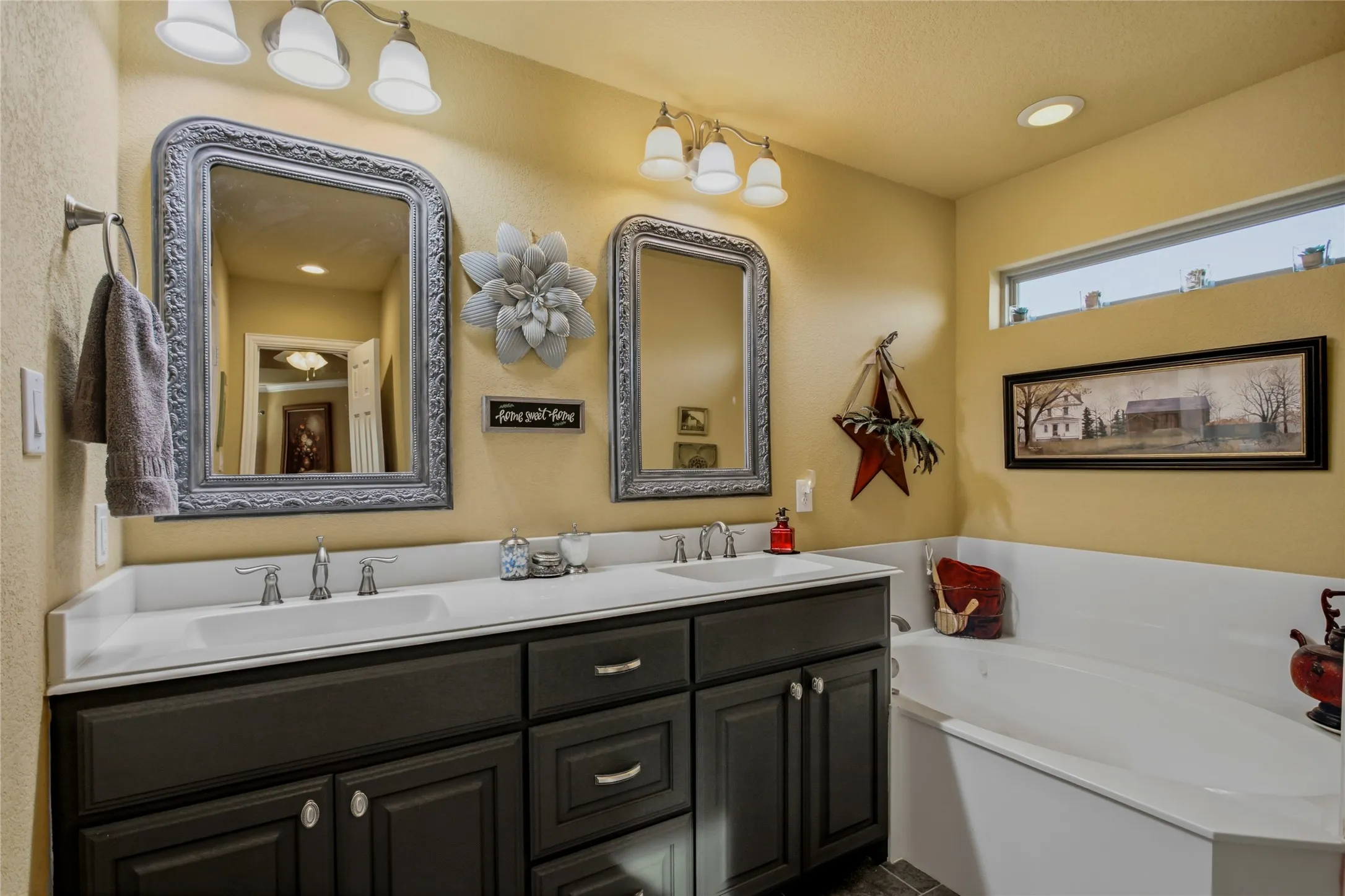 Dual sinks and a soaking tub with a nice window for natural light complete this bath area.