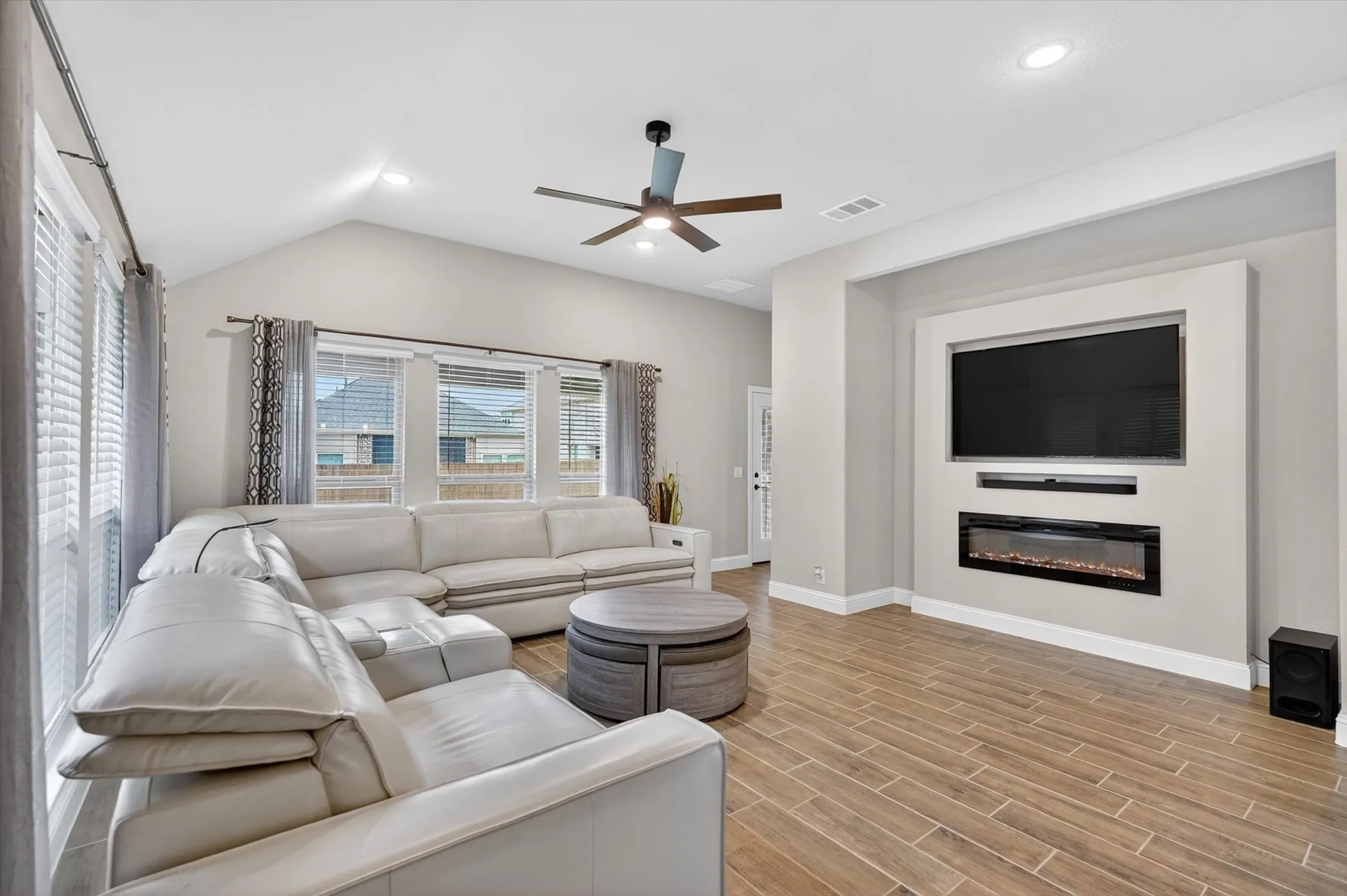 Vaulted ceiling with recessed lighting and a ceiling fan, wood-finish flooring, and multiple windows