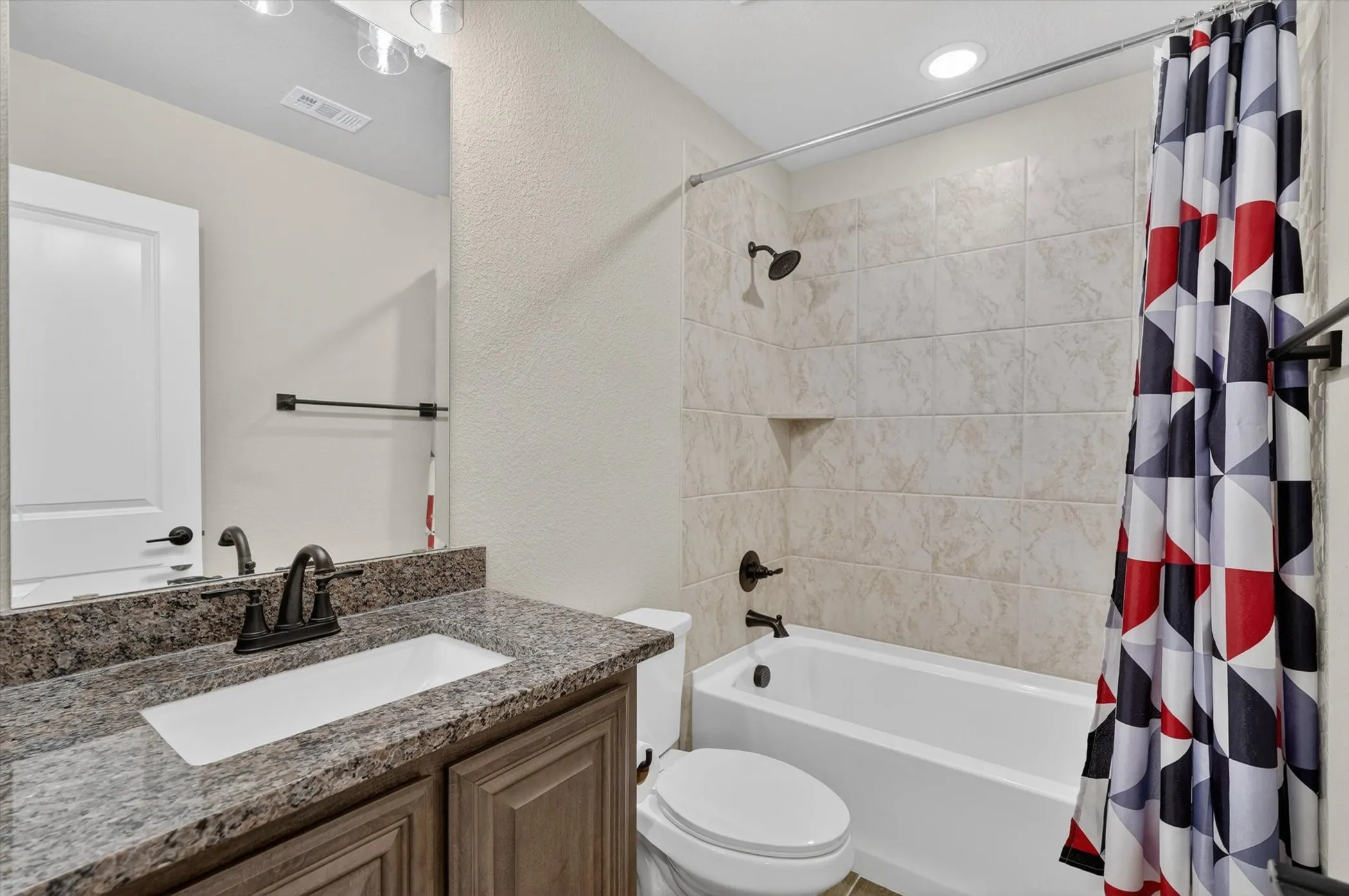 Vanity with a speckled countertop, undermount sink, and dark bronze-finish faucet