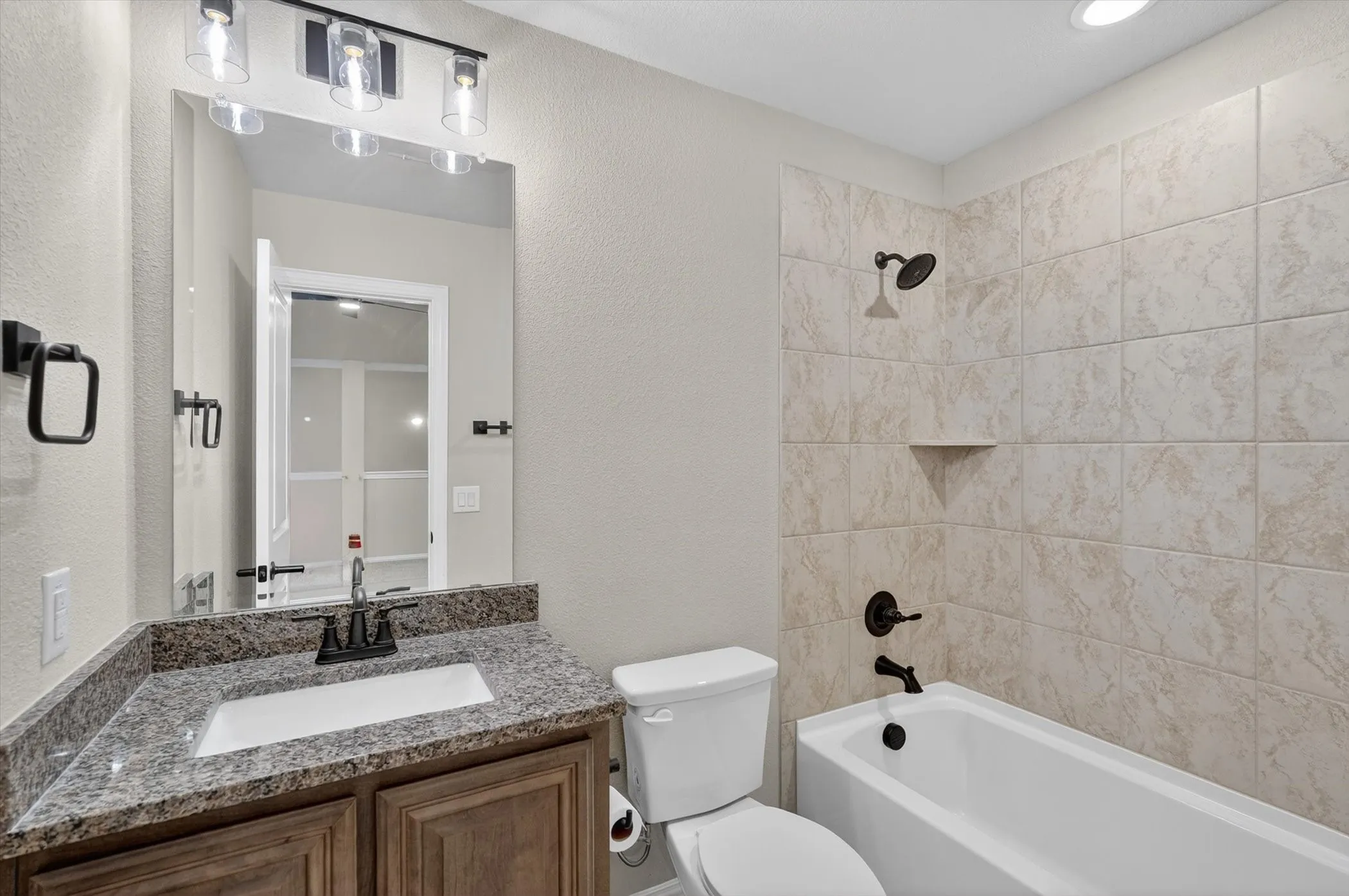 Wood-finish vanity with a granite-style countertop, undermount sink, and matte black faucet