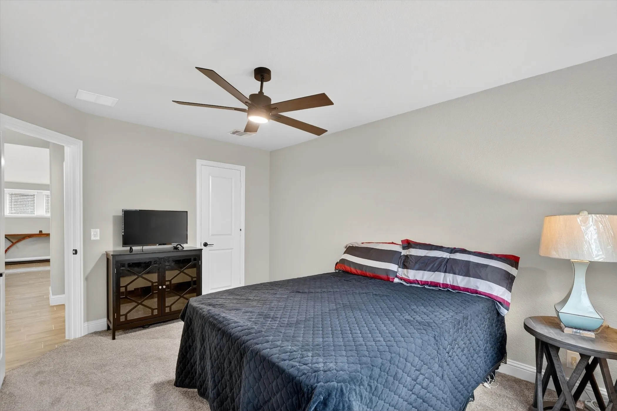 Neutral wall tones, carpet flooring, a ceiling fan, and a white interior door