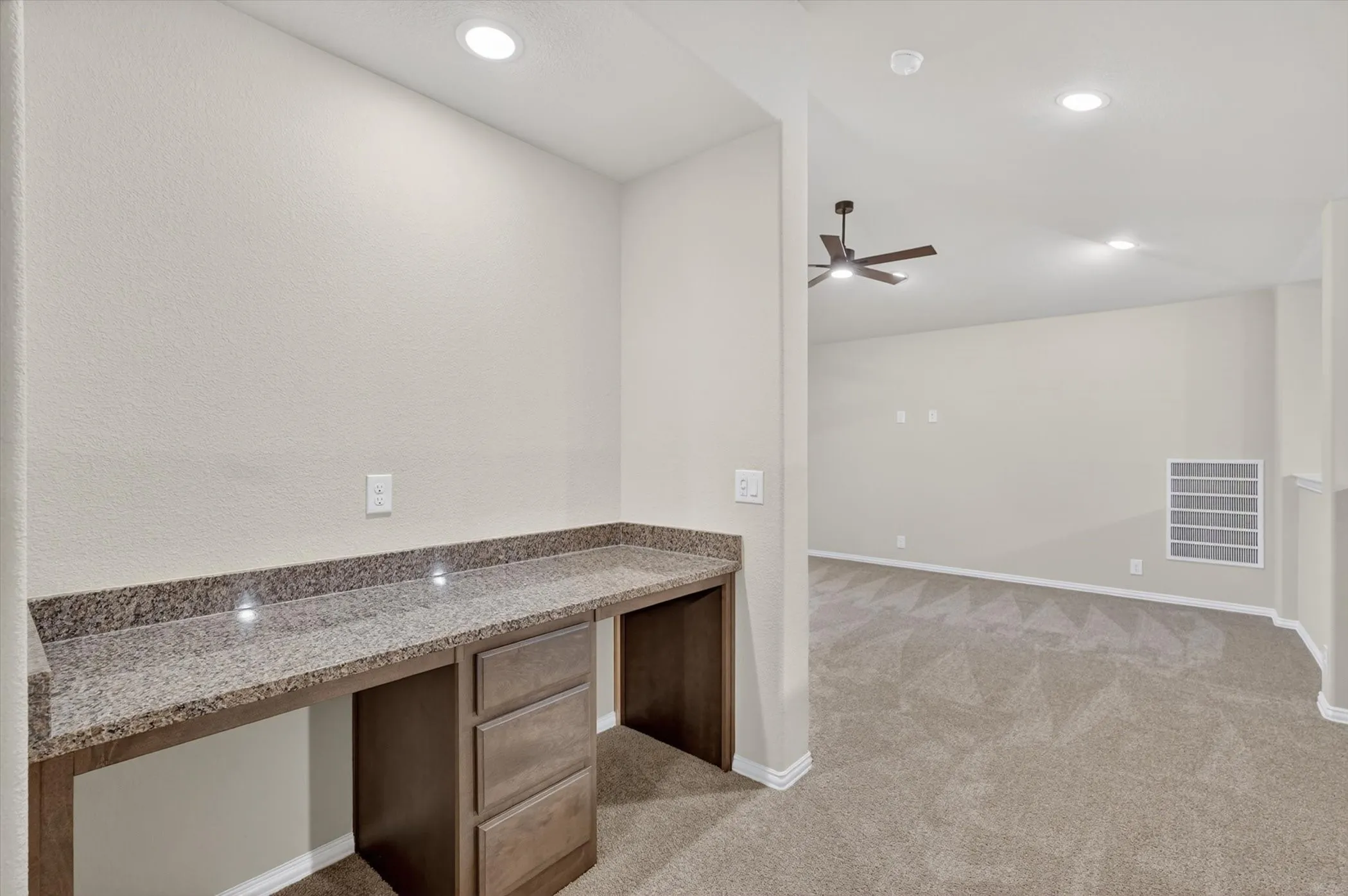 Built-in desk with a granite-style countertop and integrated cabinetry, recessed lighting, and a ceiling fan