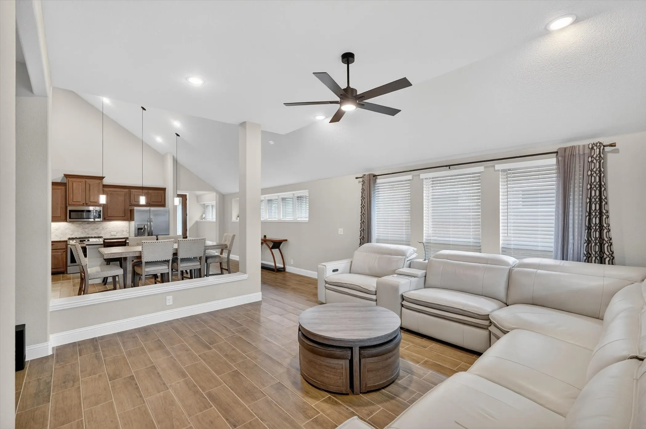 Vaulted ceilings, wood-finish flooring, recessed lighting, and a contemporary ceiling fan