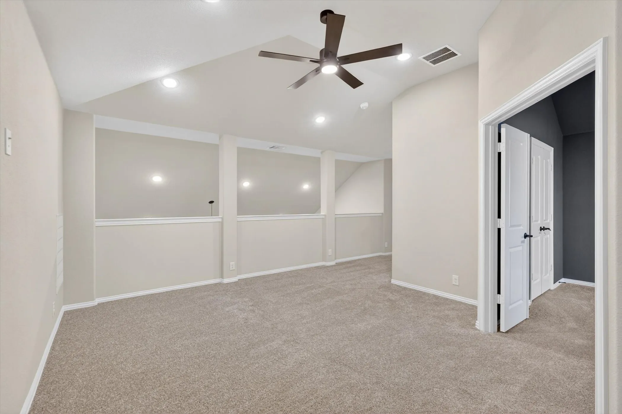 Spacious finished room featuring neutral carpeting, recessed lighting throughout, and a contemporary ceiling fan with brushed metal finish
