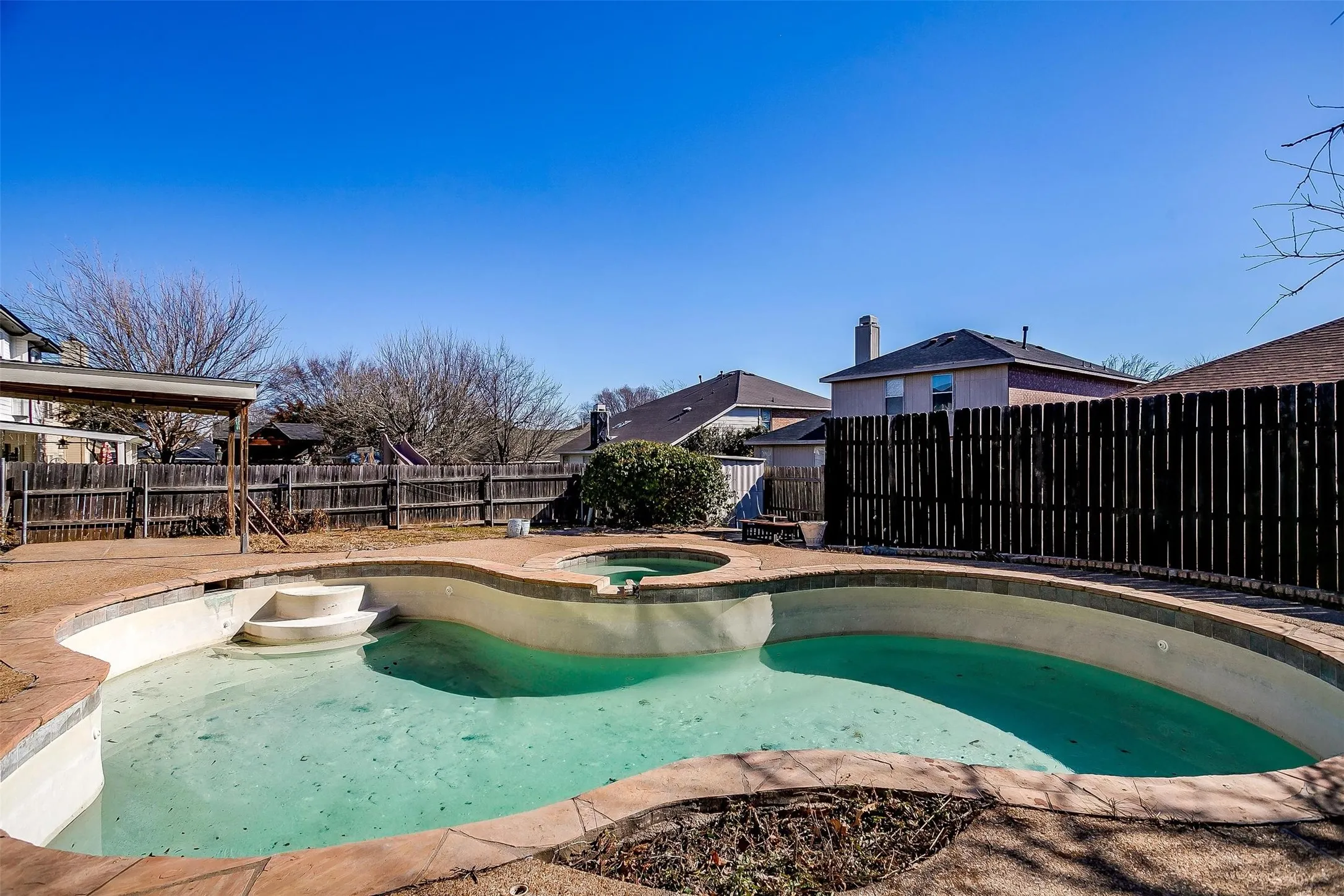 In-ground swimming pool with integrated spa, concrete deck surround, and privacy​​‌​​​​‌​​‌‌​‌‌​​​‌‌​‌​‌​‌​​​‌​​ fencing