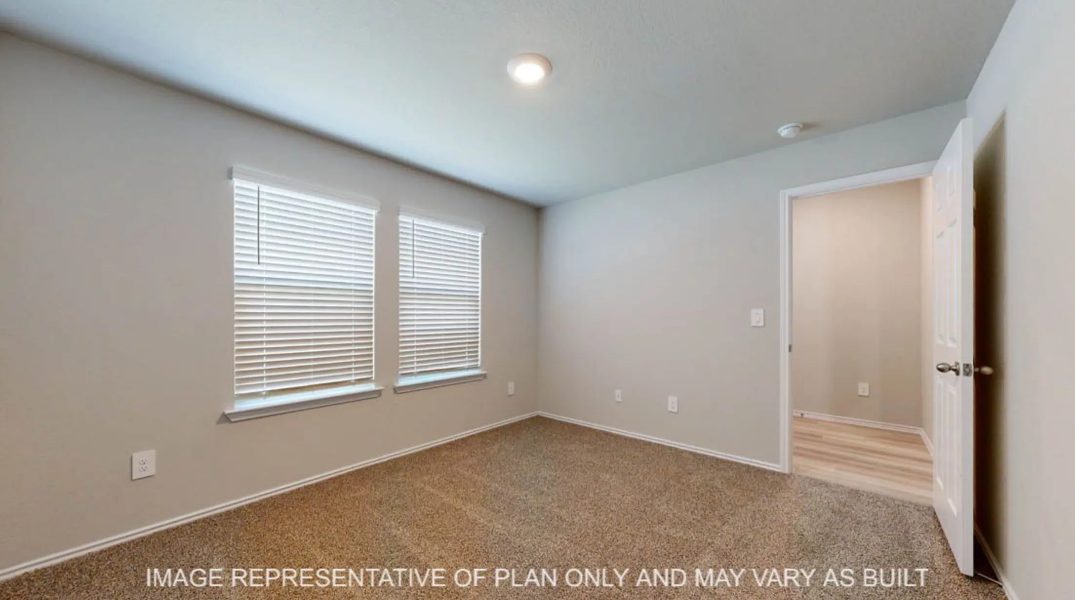 Bright secondary bedroom with dual windows featuring plantation shutters, wood-finish flooring, neutral paint finishes, recessed ceiling lighting, and direct hallway access