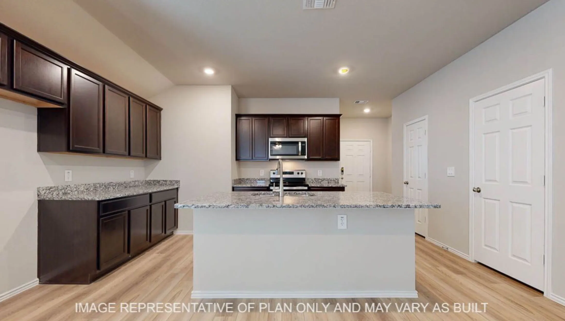 Kitchen featuring a central island, dark wood-finish cabinetry, light-toned countertops, stainless steel appliances, and wood-finish flooring